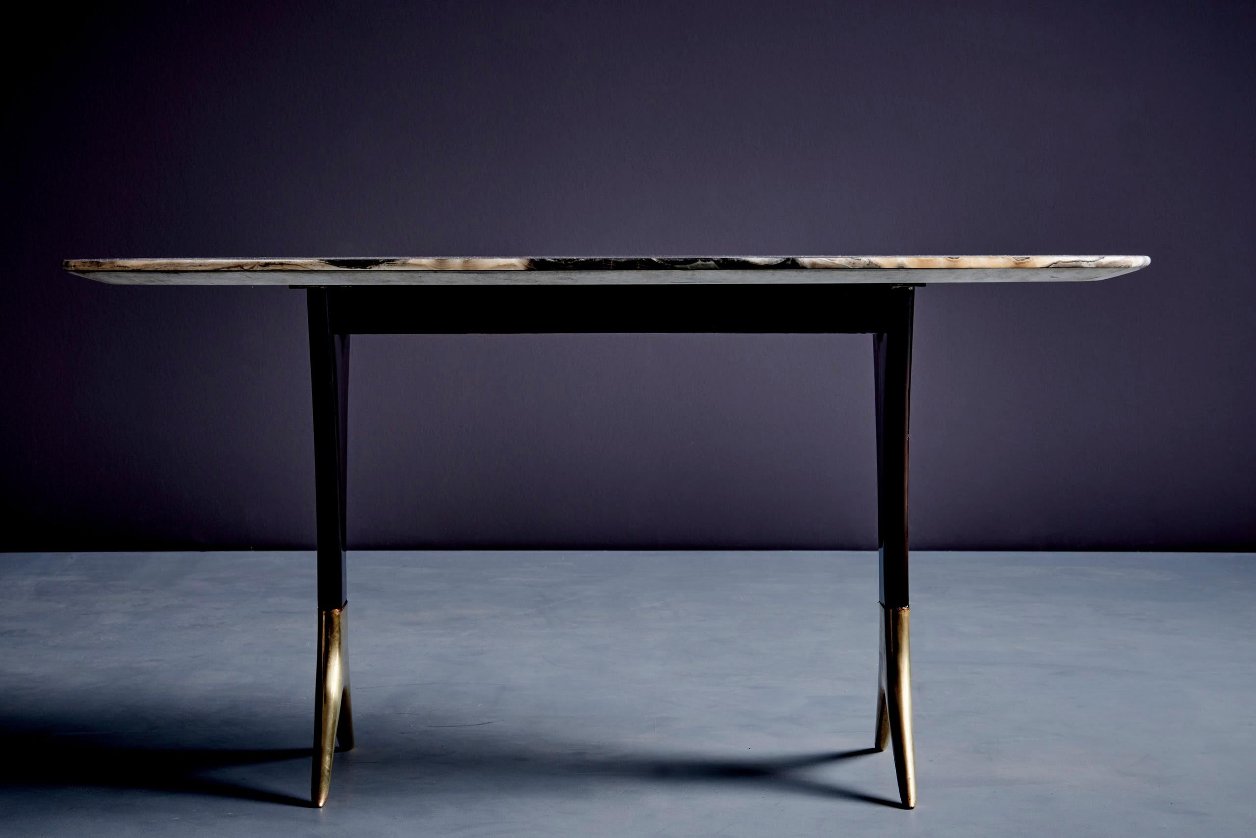 Rare table basse italienne de Guglielmo Ulrich. La base a des pieds en bois effilés qui se terminent par des pieds en laiton moulé. Le plateau de la table est en onyx richement décoré. Il présente des tourbillons organiques dans les tons noir,