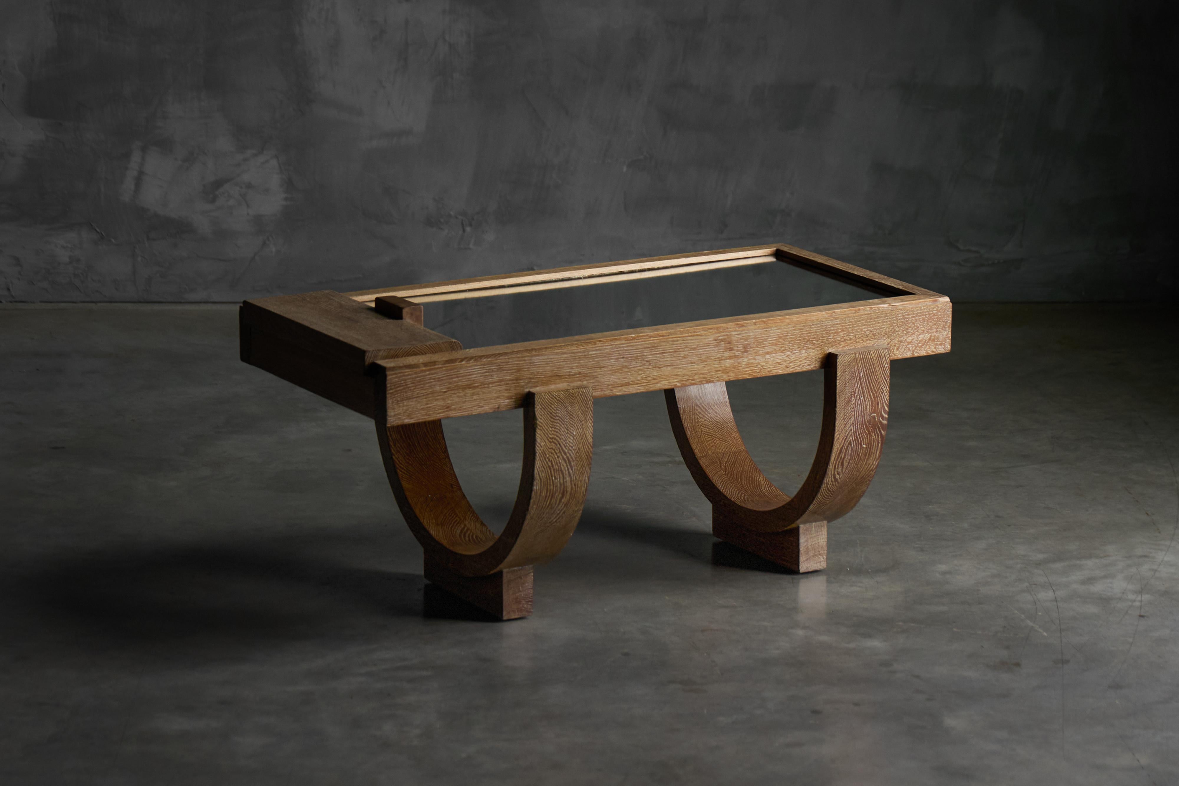 Esta llamativa mesa de centro de roble de los diseñadores franceses Guillerme et Chambron personifica la artesanía europea de mediados del siglo XX. La mesa presenta una base distintiva formada por dos elegantes arcos de medio punto, que crean una