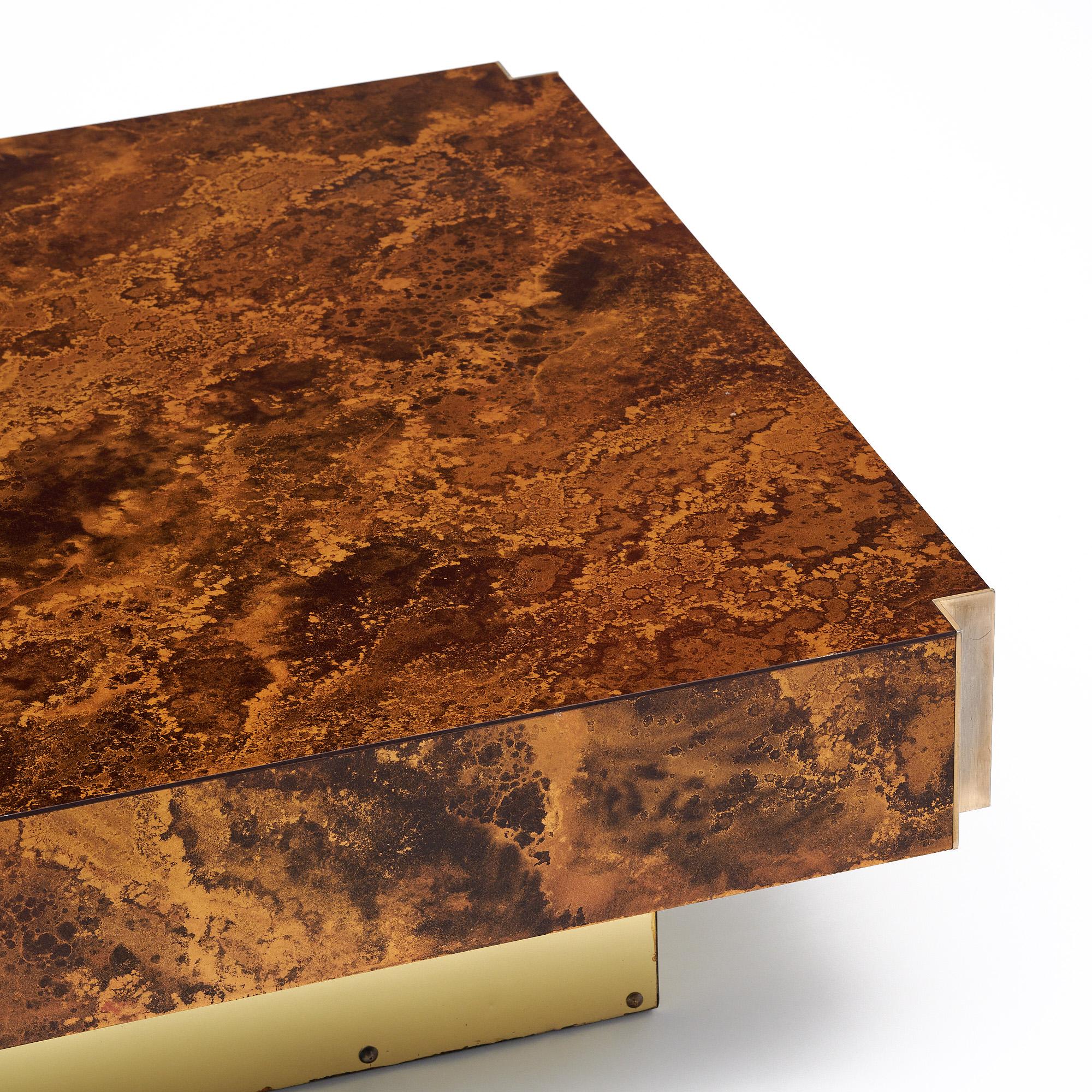 Table basse de France en bois ronceux laqué. Le plateau repose sur une base recouverte de laiton. Les coins sont en laiton pour plus de détails. Cette magnifique table a été conçue par Guy Lefevre pour Ligne Roset.
