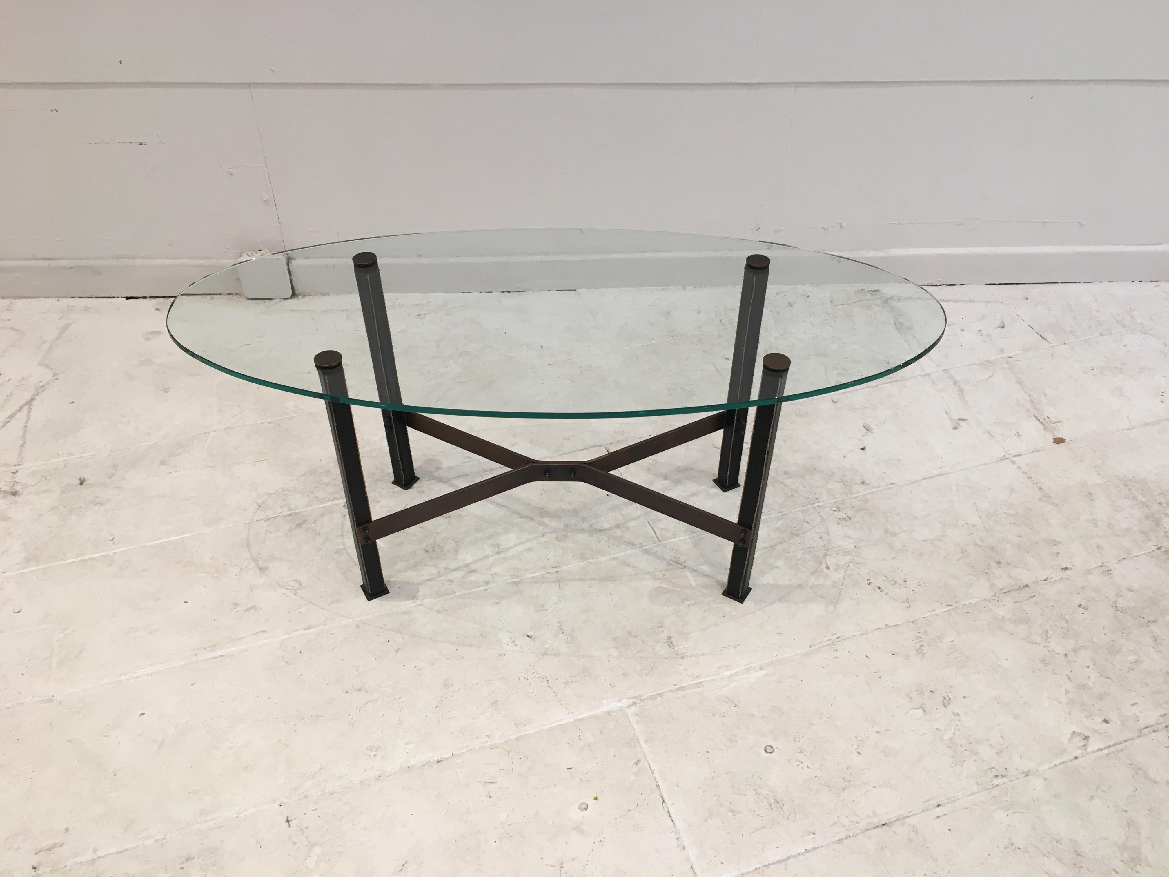 Model Canasta by Mathieu Matégot, circa 1960.
Coffee table with four square section legs covered in black leather with saddle stitching. Brass cruciform spacer and oval shaped new glass top.