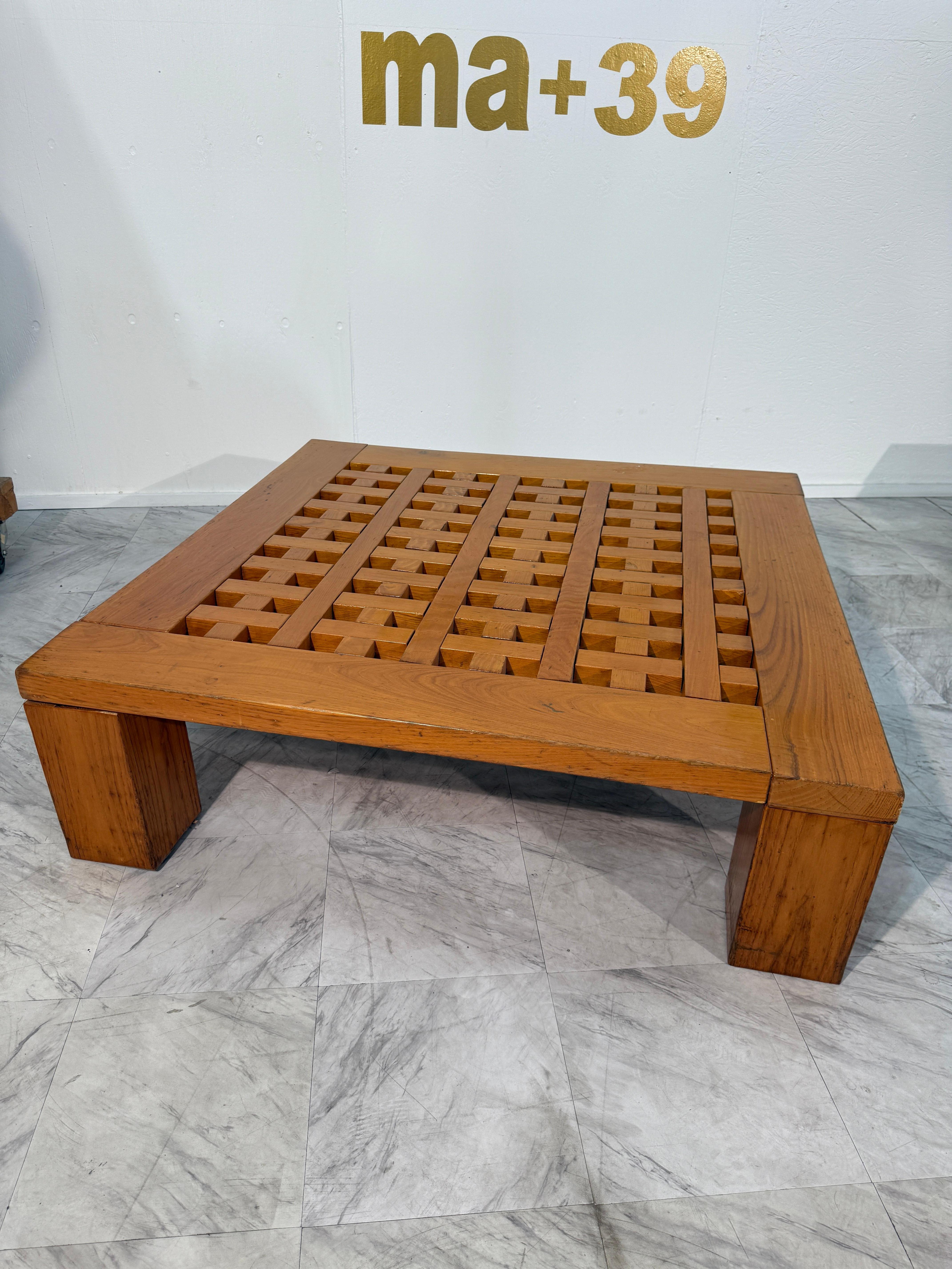 Table basse italienne par Meccani Studio pour Carabotto, présentant une forme carrée audacieuse avec un plateau en treillis en bois massif et des pieds en blocs robustes. Un mélange raffiné d'artisanat et de design moderniste, offrant à la fois une