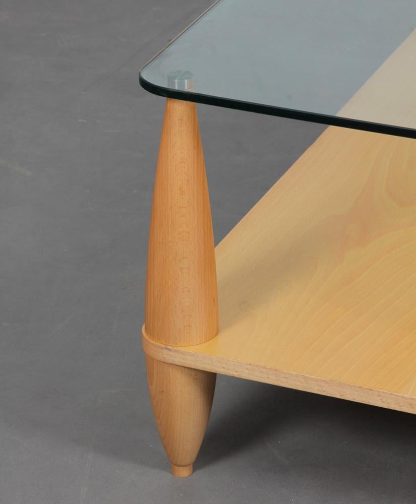This coffee table has a wooden top and a glass top supported by legs at the four corners, as well as a central leg. Il est en bon état d'origine. 