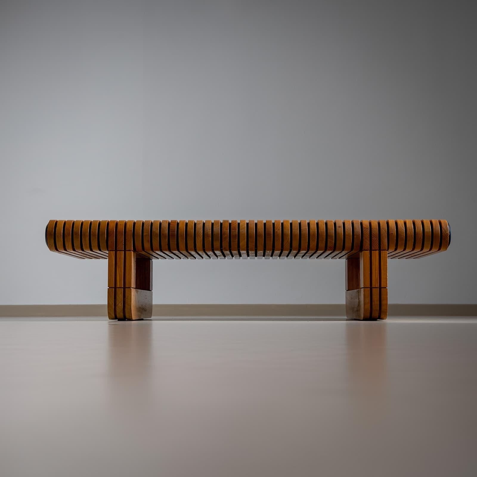 Coffee table made of rounded slats with skid-shaped legs and black metal discs that bind the individual wooden slats together. The solid, heavy wooden table was designed by Paolo Piva (1950-2017) in 1974.  