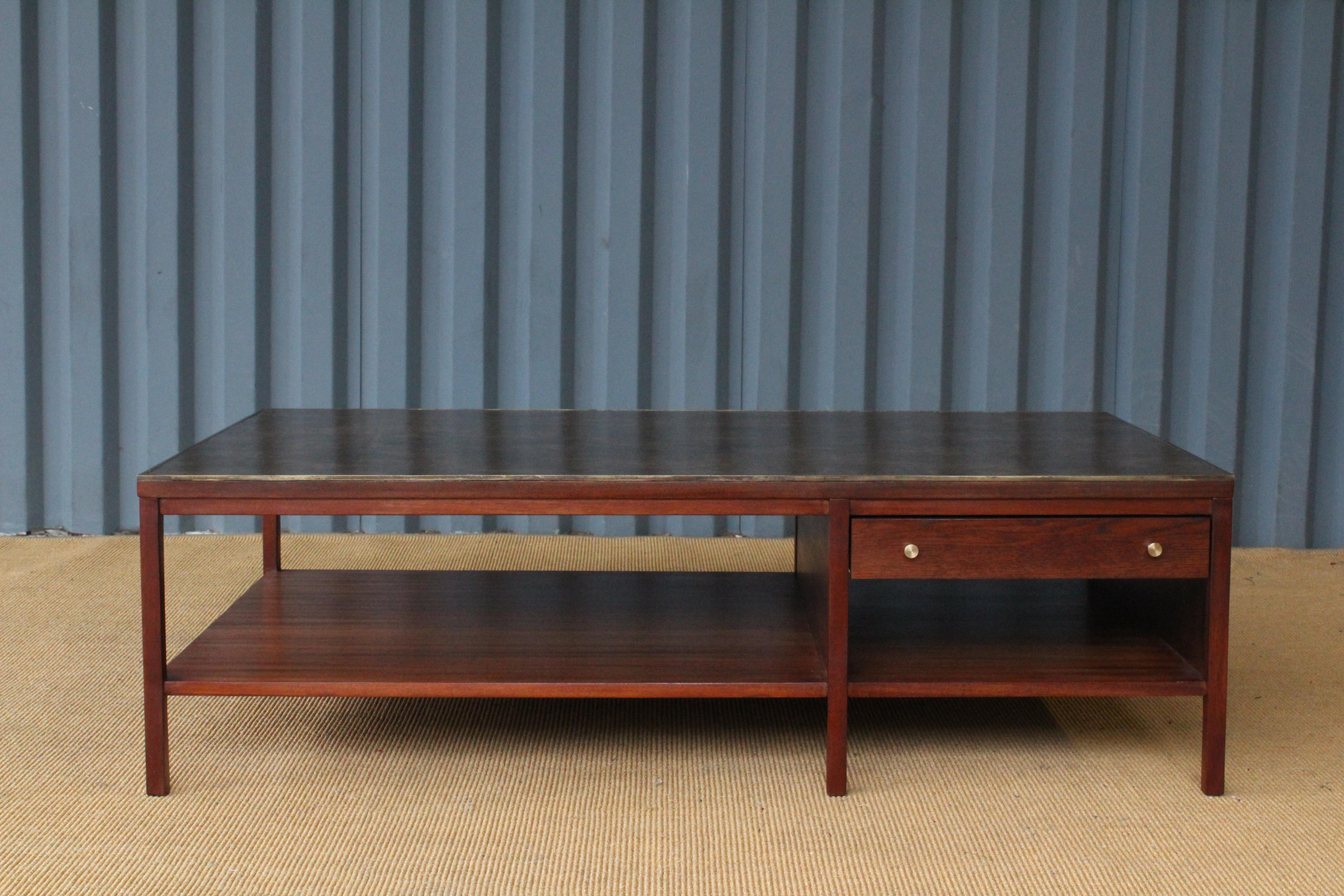 Mahogany coffee table designed by Paul McCobb for Calvin Furniture, 1950s. Features brass trim around the original leather top. Two drawers with brass pulls. Recently refinished. Leather surface shows a few minor signs of wear.
 