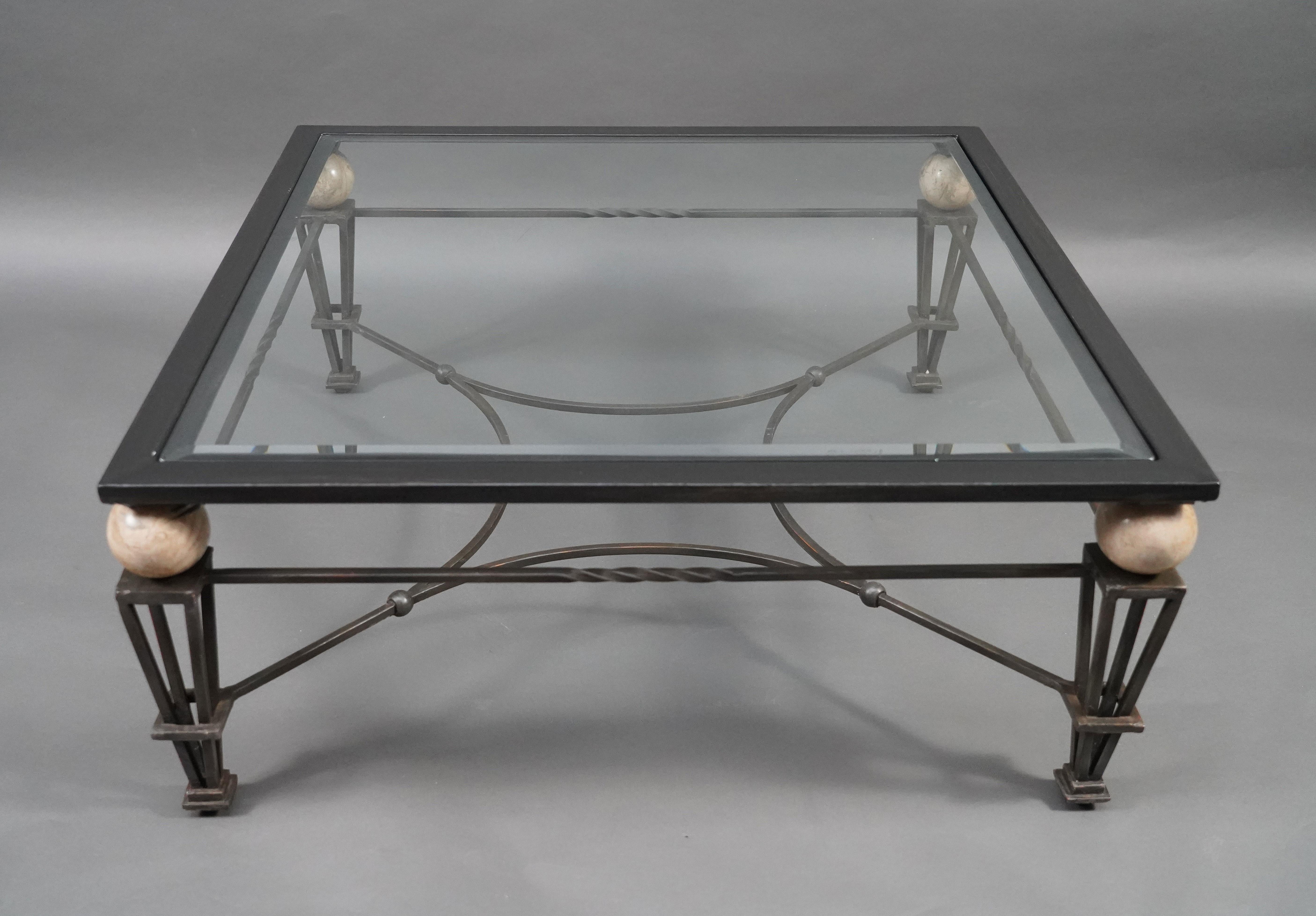 Beautiful patinated iron coffee table. The square beveled glass top rests on four marble balls ending in four openwork sheathed feet, connected by a spacer.

Biographie :
Roche Bobois is the story of how the managers of two stores met in the 1960s