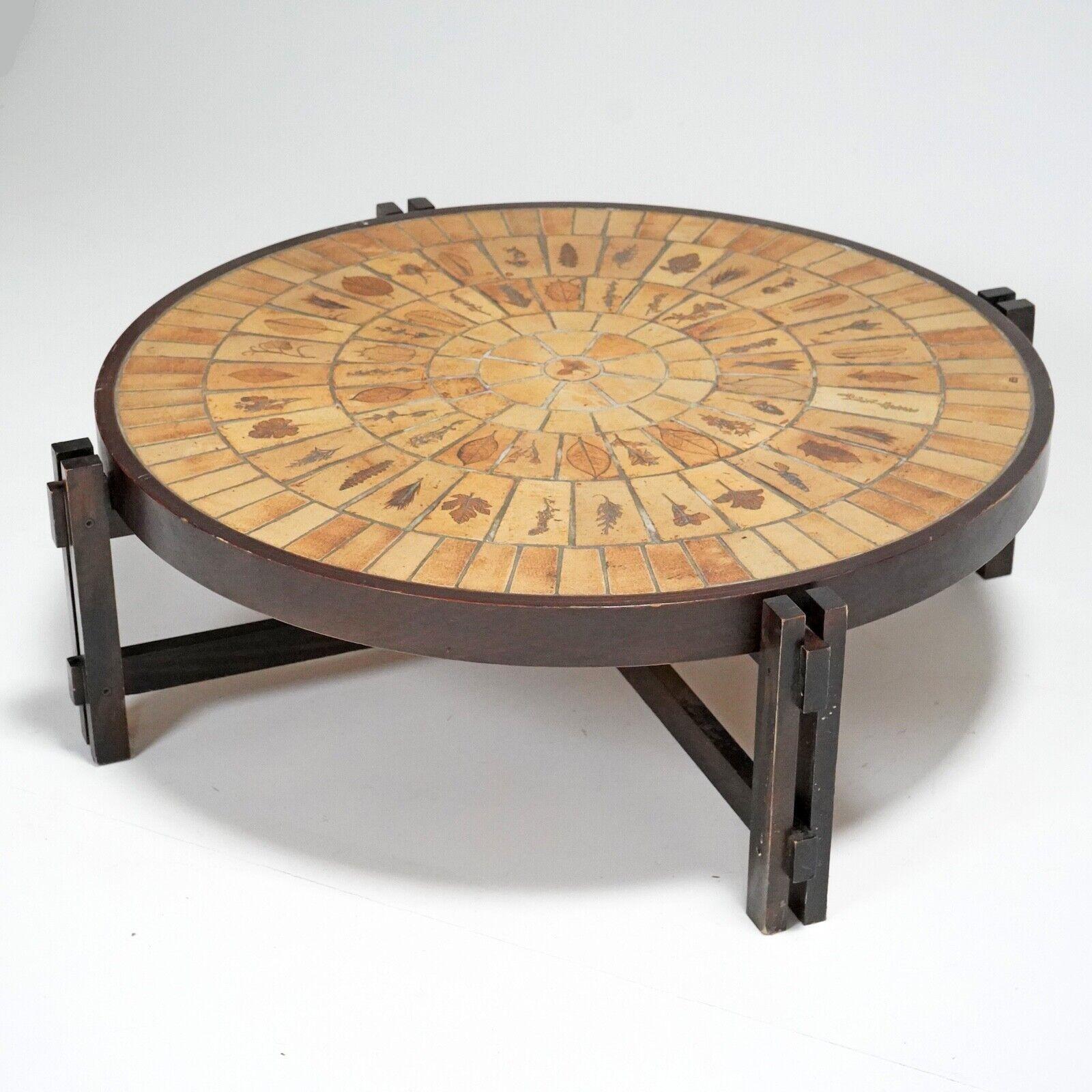 Roger Capron tile top coffee table with constructivist oak base.
The sand stone tiles are embedded with plants from the south of France which leave their natural imprint. 
Dating from the 1960s and stamped Capron, Vallauris, France.

Condition