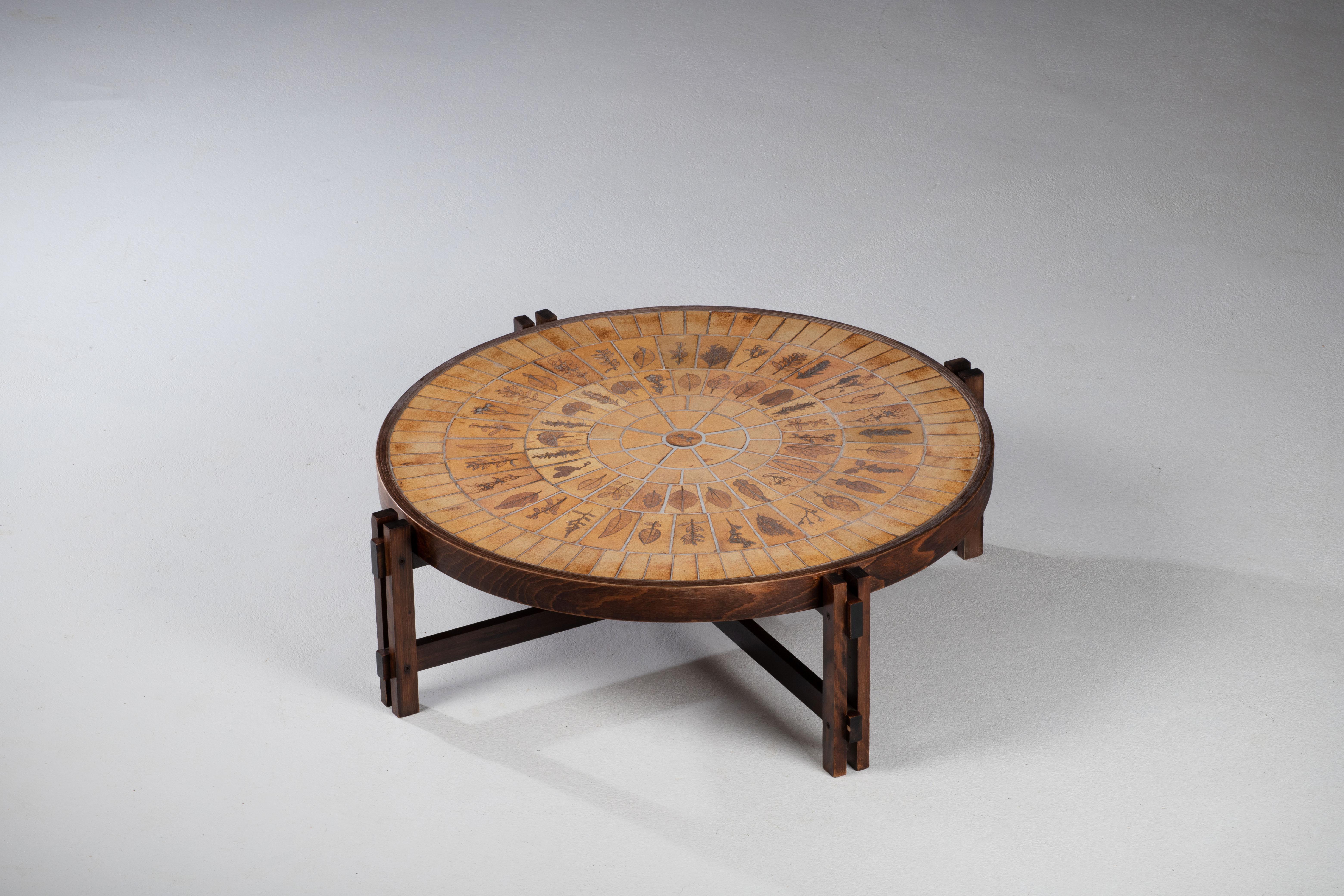 Coffee table, “Garrigue” model, round shape, top in ceramic tiles decorated with leaves, with a constructivist base in oak.
The 
