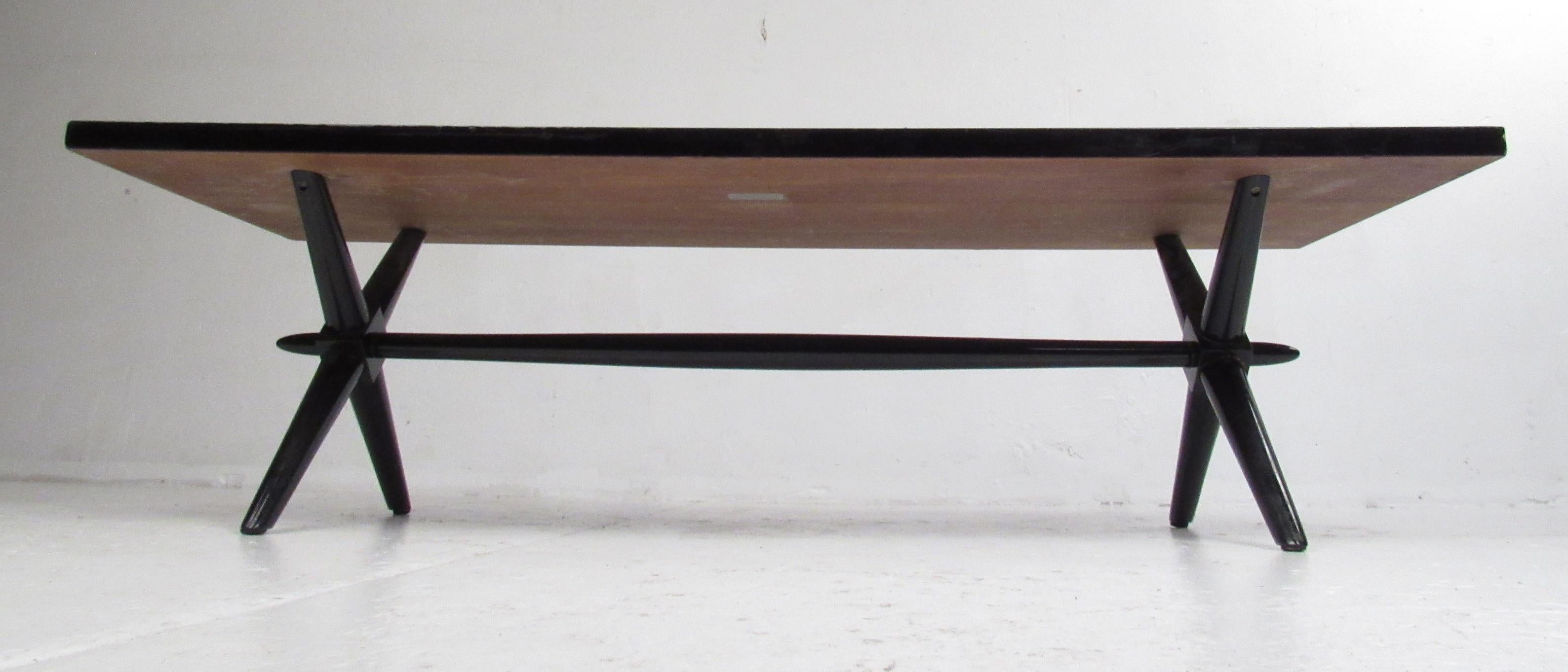 Low black ebonized coffee table on a X-shaped base by British born designer and interior decorator T.H. Robsjohn-Gibbings (1905–1976). Please confirm item location (NY or NJ) with dealer.
     