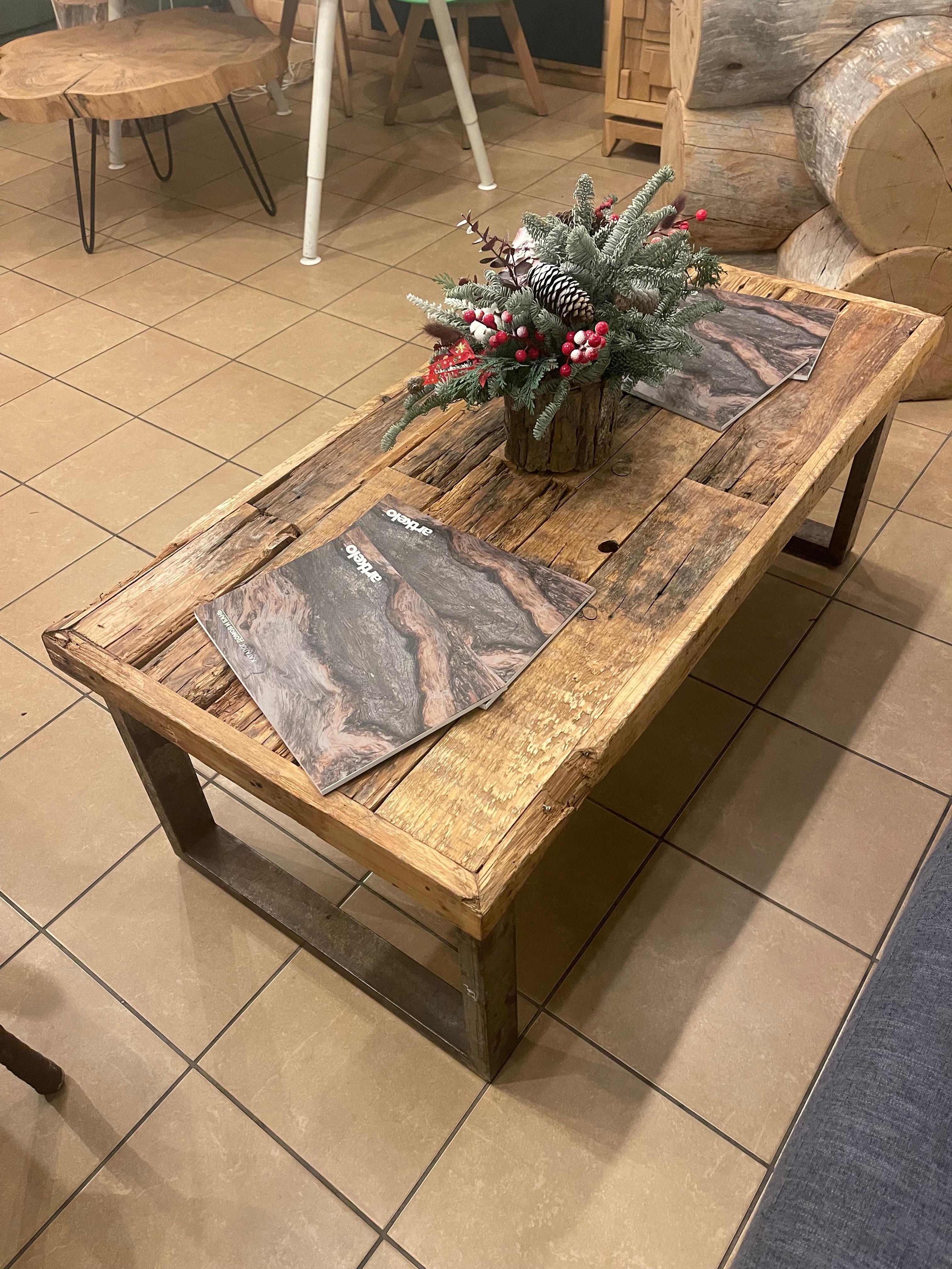Ein restaurierter Couchtisch aus aufgearbeitetem Scheunenkiefernholz. Handgefertigt aus osteuropäischem Scheunenholz, das eine einzigartige, geschichtsträchtige Textur aufweist. Der Metallsockel mit patinierter Oberfläche unterstreicht den