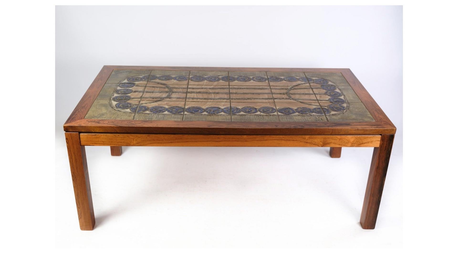 The coffee table adorned with tiles in rosewood Danish design from the 1960s is a stunning example of mid-century modern craftsmanship and style. This piece combines the warmth and richness of rosewood with the artistic beauty of tiled decoration,