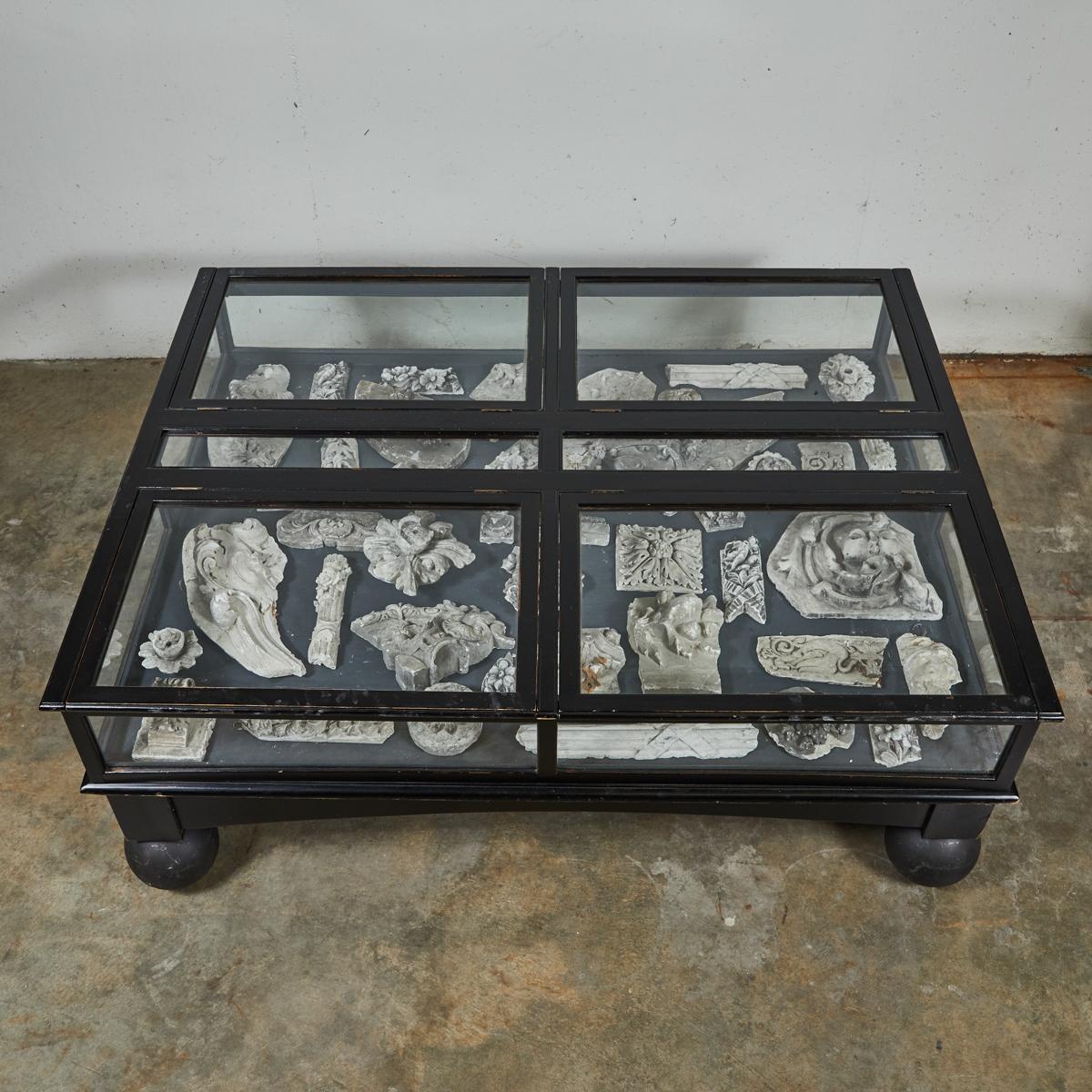 Late 19th-century English glass display case table with round ball feet. A compelling conversation piece, this display case--perfect in size for use as a coffee table--features black wood trim and a gray interior. Ideal for displaying your own
