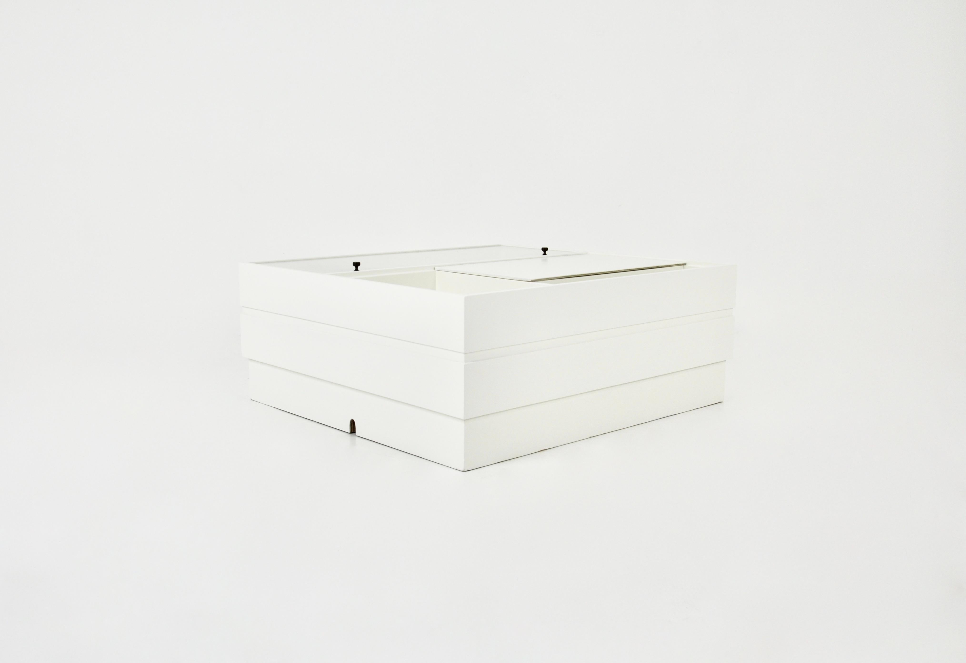 Table basse en bois blanc avec un compartiment pour un tourne-disque, un compartiment pour ranger des disques vinyles et deux espaces de rangement, dont l'un est en verre. Des trous sont faits pour le tourne-disque et pour les connexions. Usure due