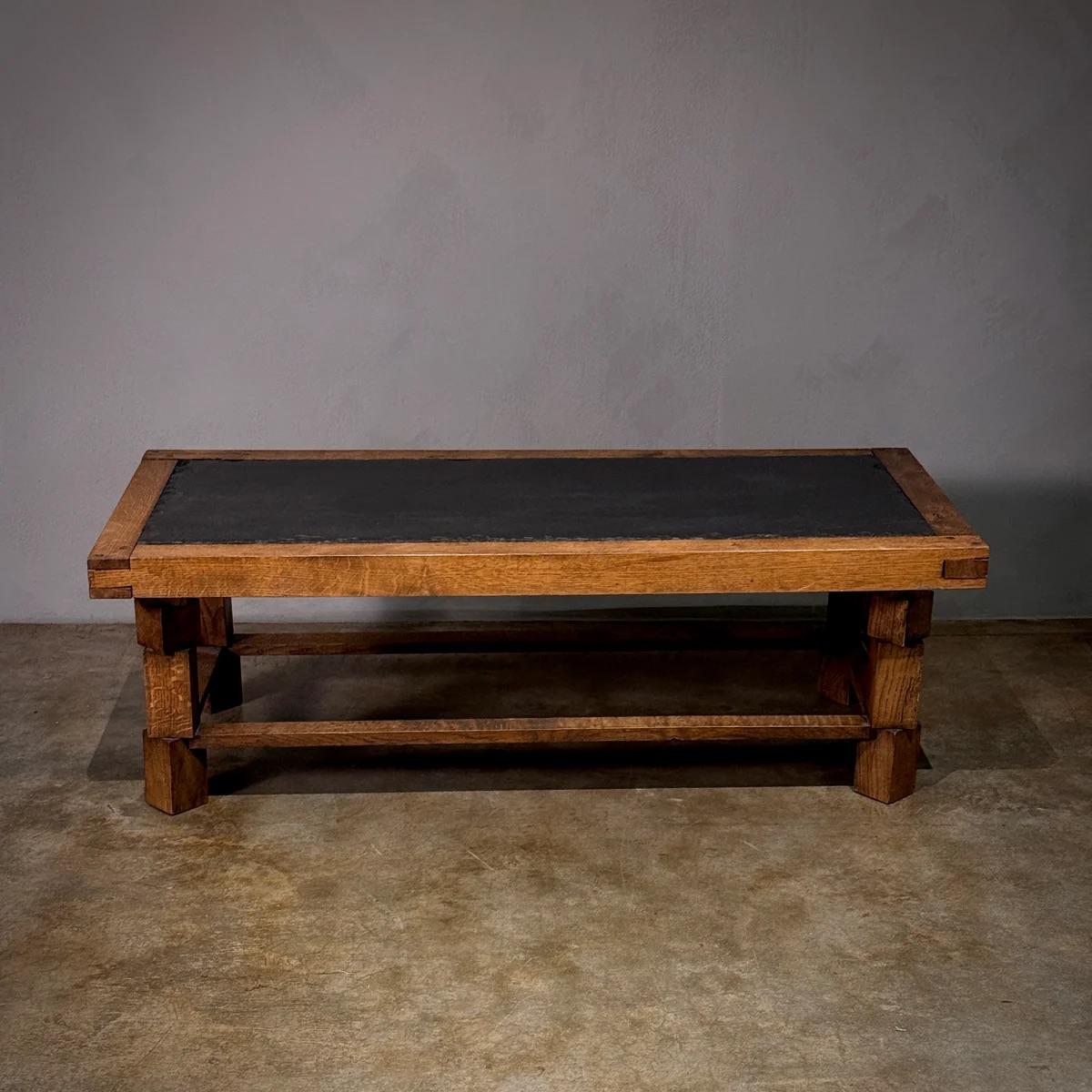 Table basse avec structure en chêne massif et plateau en ardoise noircie. Les détails bruts, martelés à la main, ajoutent un sens de l'histoire et de l'artisanat à la pièce, ce qui en fait un ajout audacieux à n'importe quel espace.