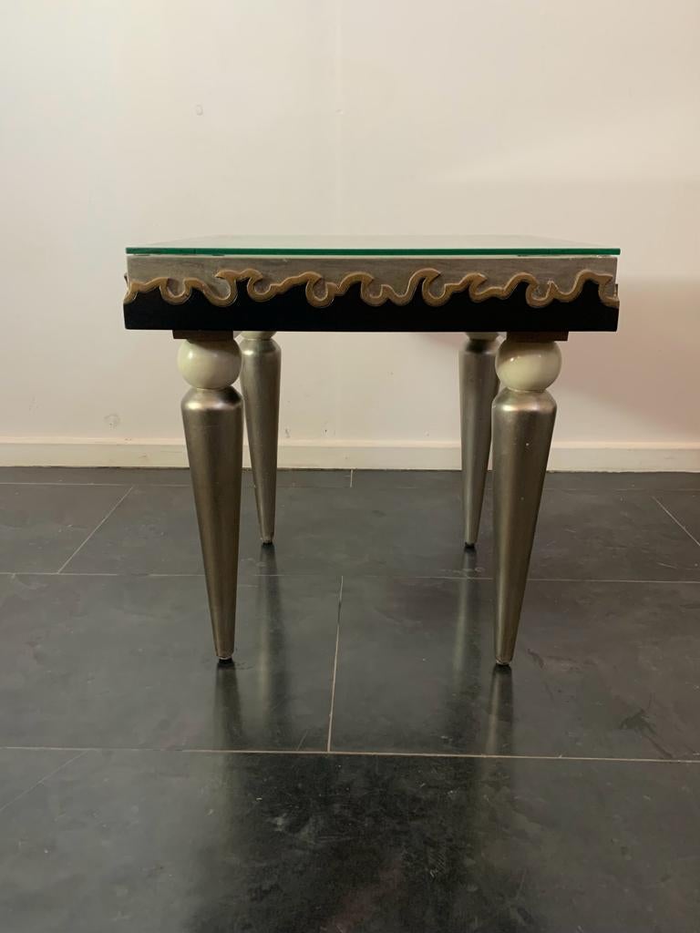 Splendid eclectic coffee table with a Dèco flavour. Conical legs ending in a sphere support the table top worked with carved and applied movable bands around and above the top. Lacquered black and ivory with silver and gold leaf