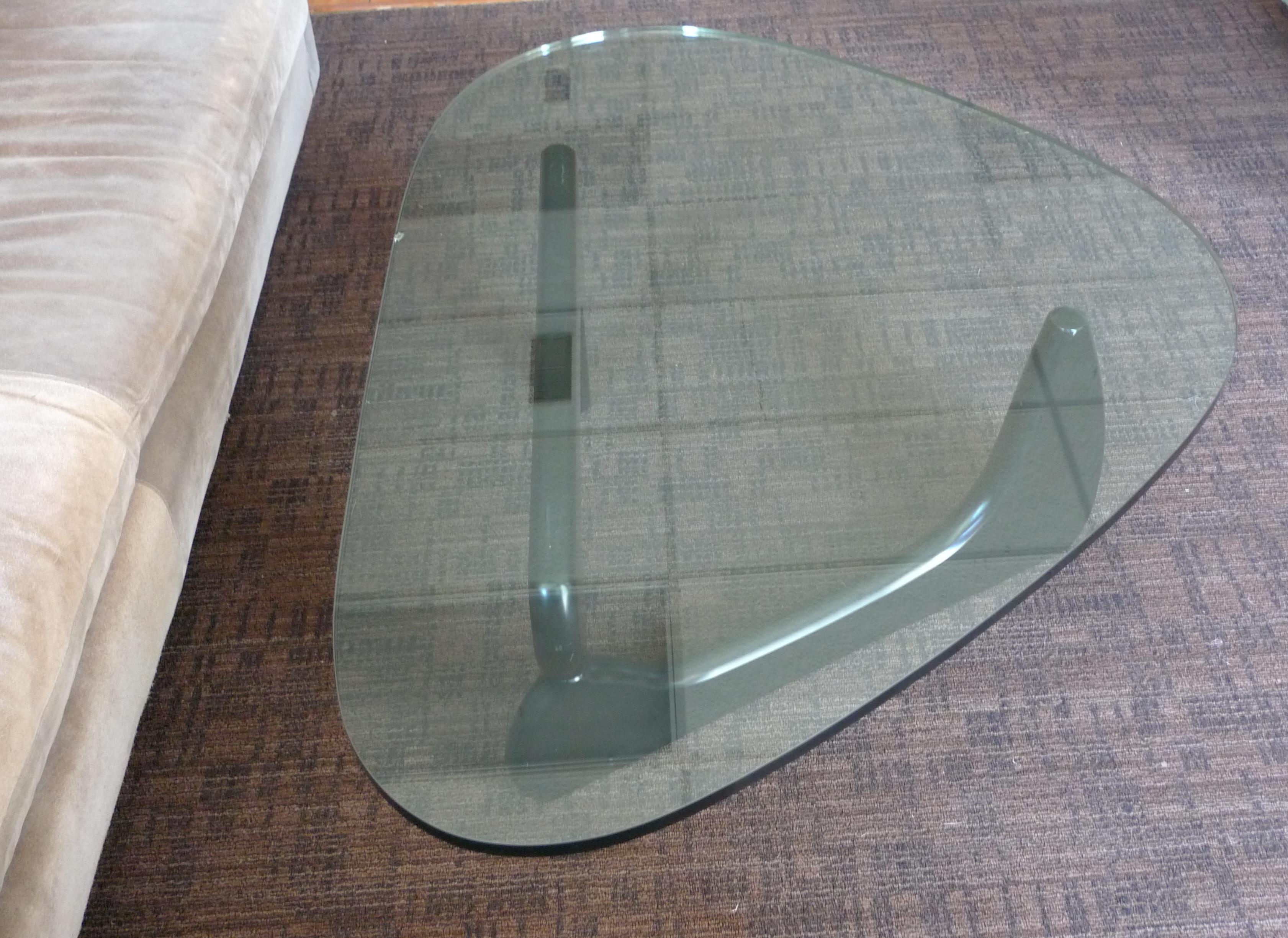 Coffee Table IN-50 Designed by Isamu Noguchi for Herman Miller, circa 1940s. An icon in the furniture world. The two curved, wooden shapes that comprise the base are mirror images inverted to provide support to the triangular glass top. The three