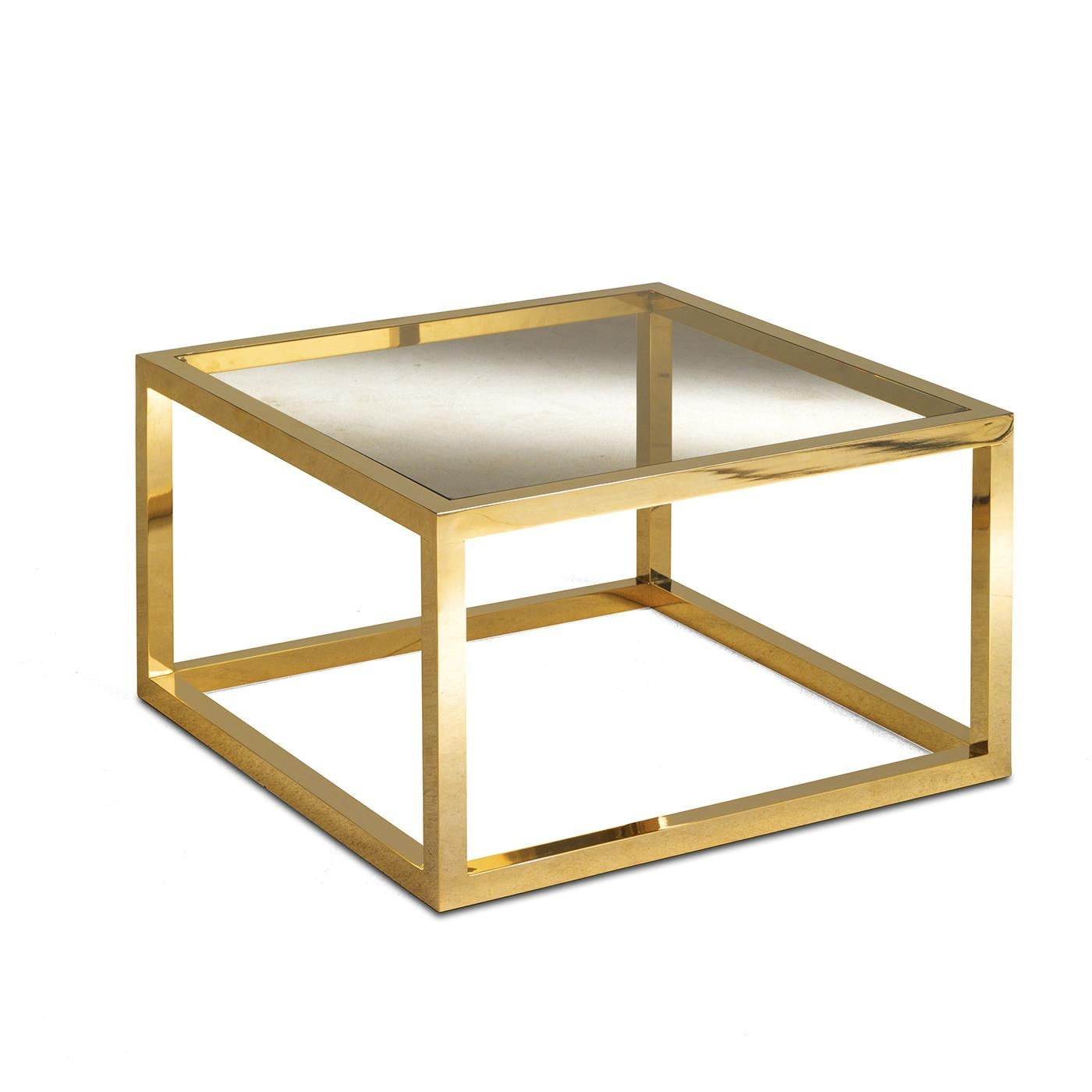 Exercice de minimalisme élégant, cette table basse présente une base carrée d'où partent quatre pieds courts qui soutiennent un plateau carré. Toute la structure est en laiton, tandis que le plateau est en verre avec une finition bronzée. Simple et