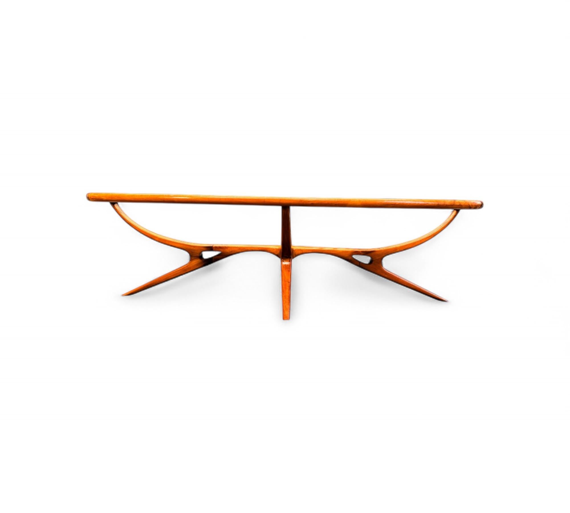 Esta mesa de centro tiene un armazón de madera dura de Caviuna y un tablero de cristal con cuatro patas. La mesa tiene forma ovalada y la madera presenta un bonito dibujo. La forma de la mesa y el estilo de las patas son lo que hace que esta pieza