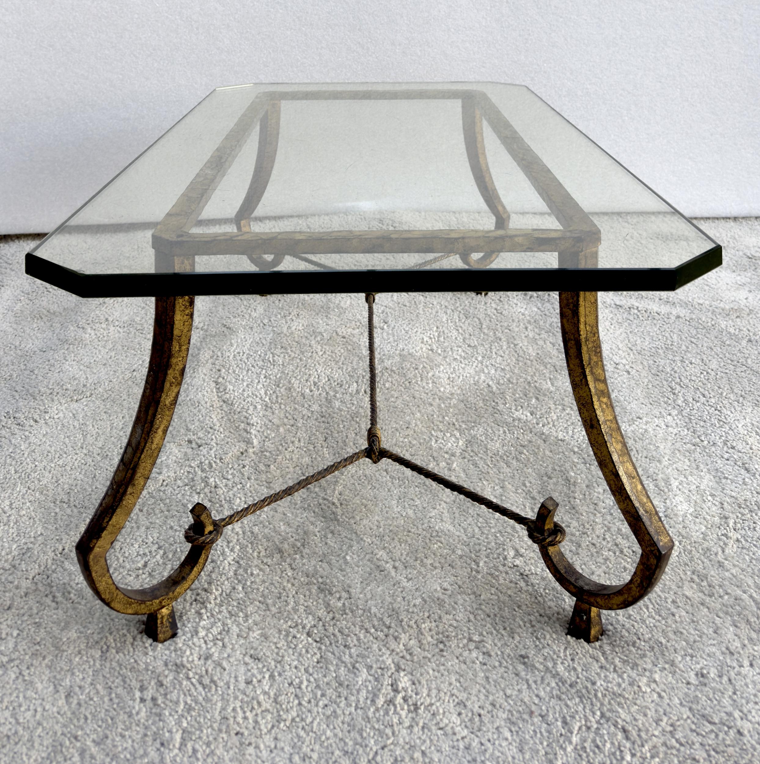 Coffee table in wrought iron, hammered and then gilded with leaf. Patina of use.
The top is a thick, angled glass top. Original with a few scratches.