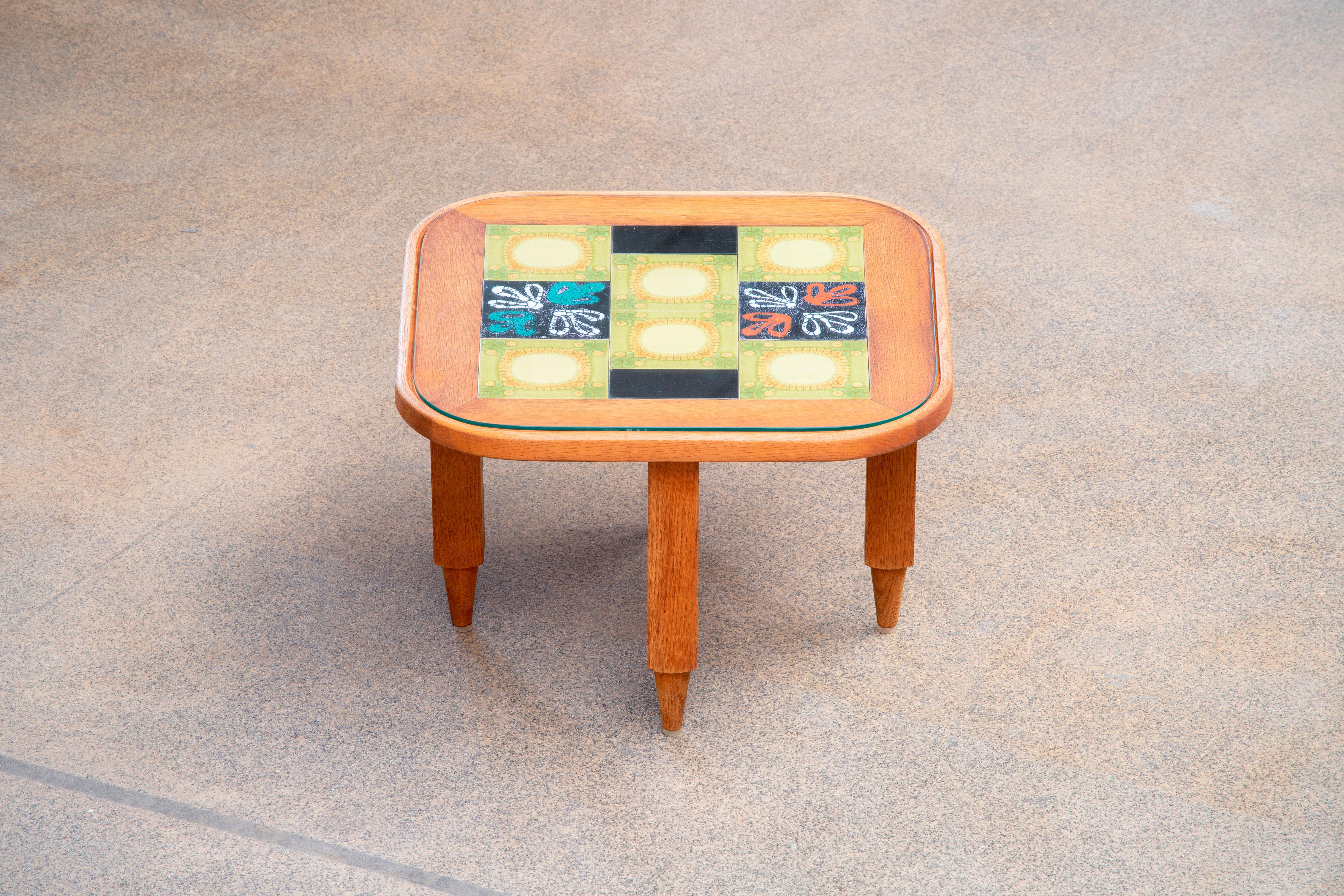 Table basse ronde en chêne avec de beaux carreaux de céramique colorés dans le plateau. Les matériaux et les formes de cette table présentent les caractéristiques des designers français Guillerme et Chambron. Ils combinent des formes classiques avec