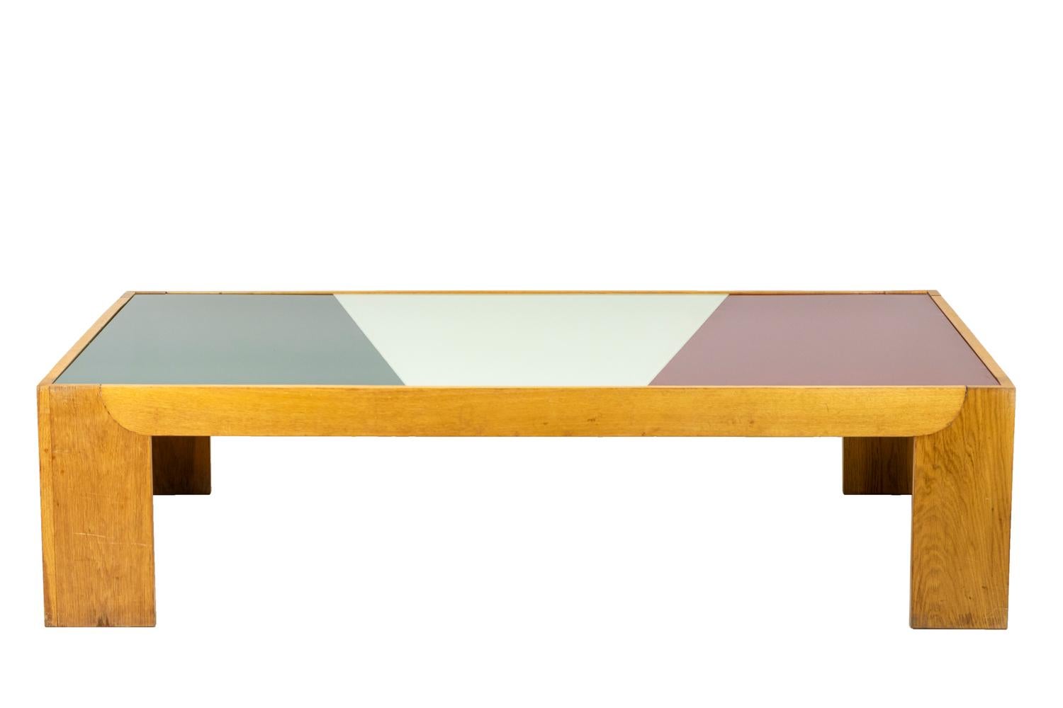 Large coffee table in blond oak.Tray composed of three glass plates tinted in green, white and red, assembled in staggered rows. Wide feet.

Work realized in the 1970’s.