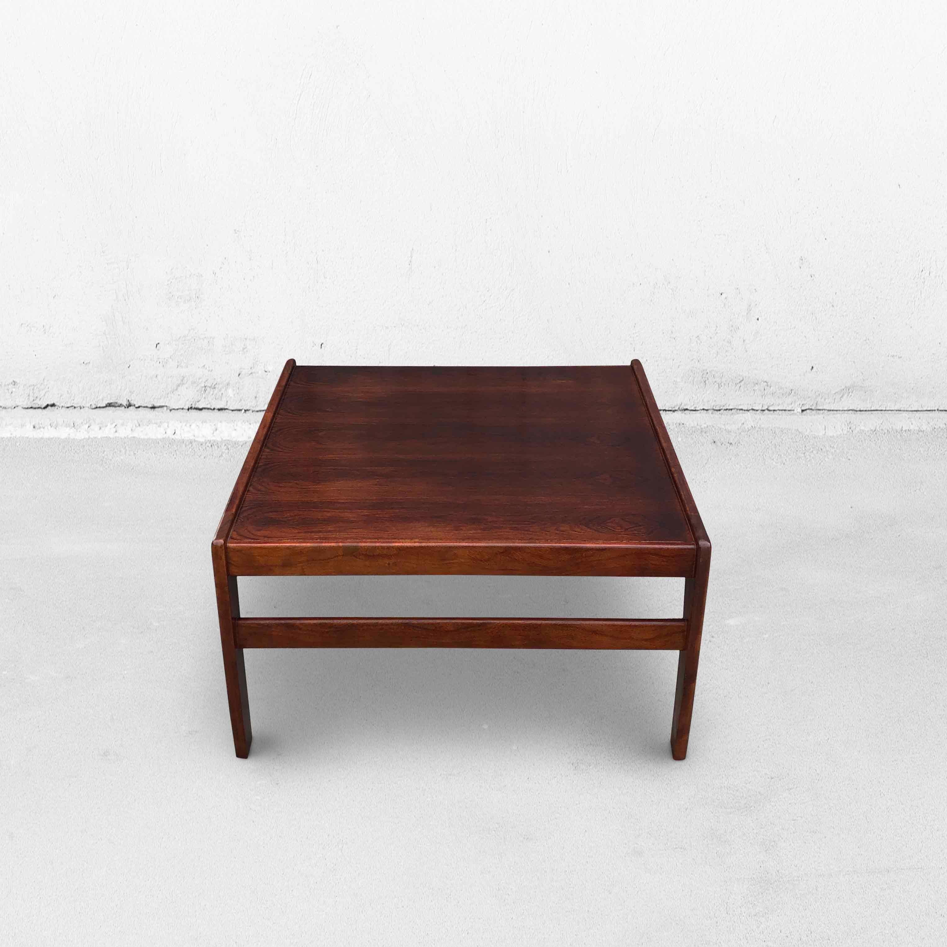 This low mid-century coffee table fits into any interior. The table is made of rosewood and has slightly curved legs. The rim is raised on two sides. This beautifully finished table has an elegant appearance. The table has a small gap along 1 side