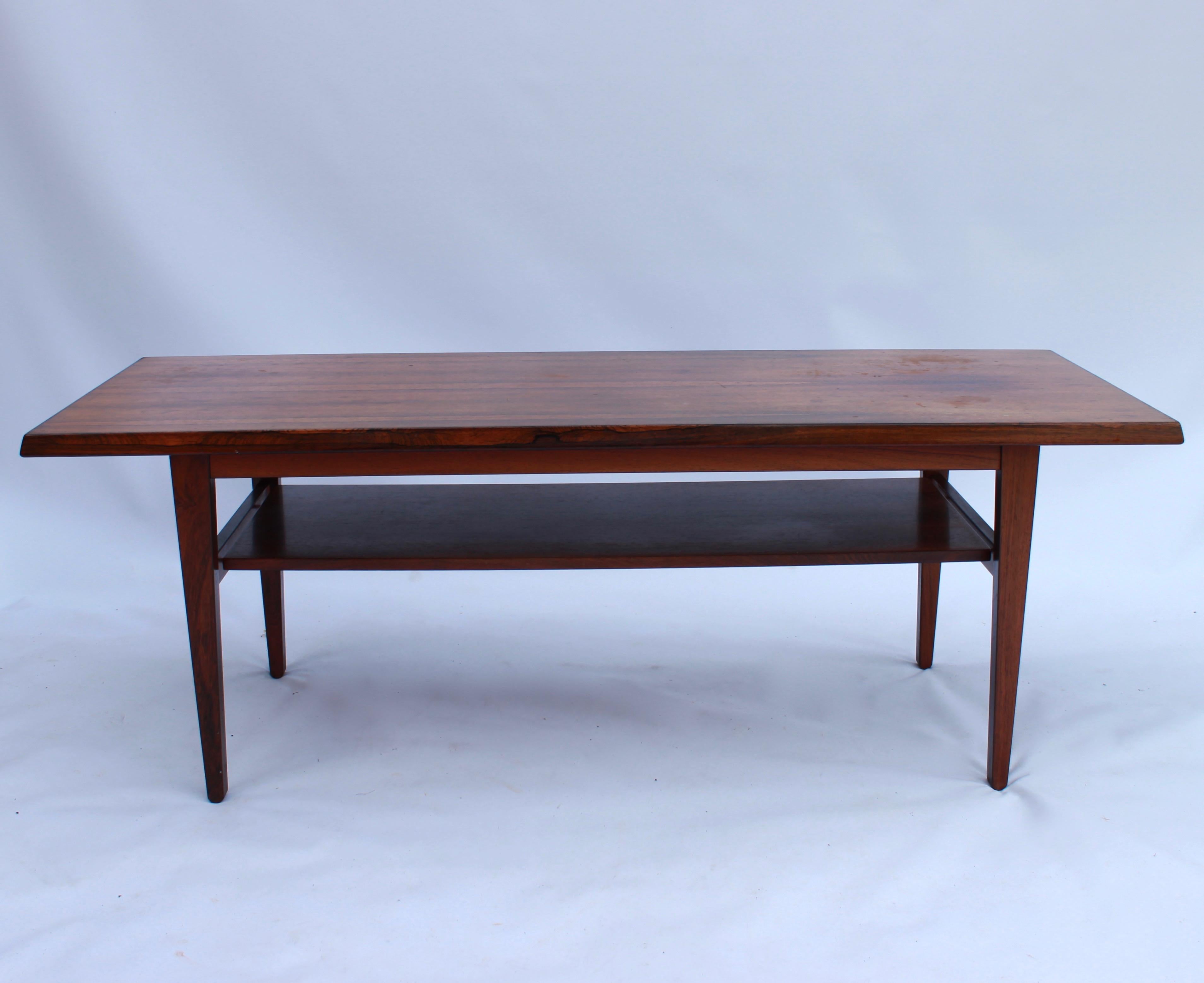 Cette table basse est un bel exemple de design danois des années 1960 et est fabriquée en bois de rose, ce qui lui confère un aspect élégant et intemporel. La table a une couleur chaude caractéristique et une structure en bois unique qui ajoute de