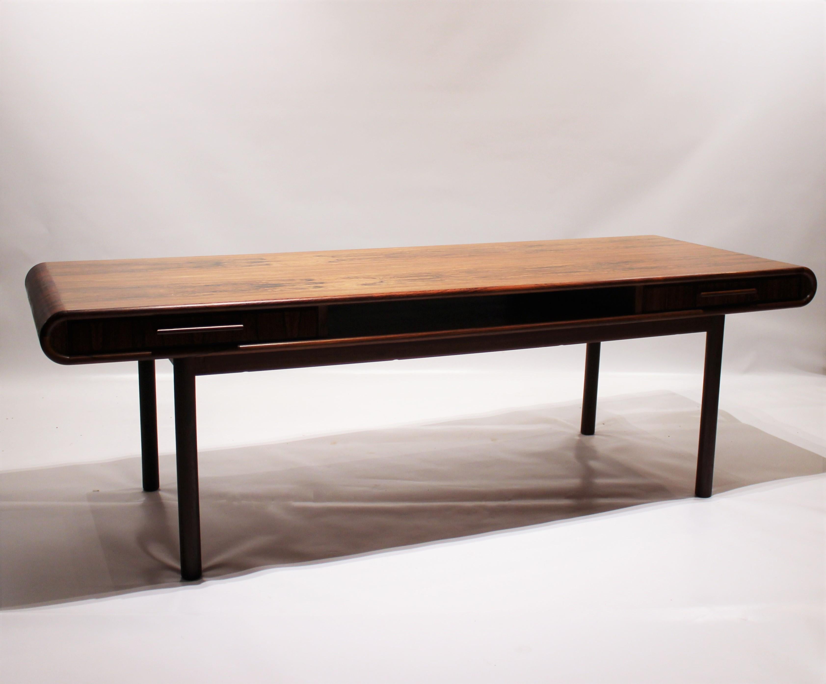 Coffee table in rosewood with curved edges of Danish design from the 1960s. The table is with an open shelf, drawers and in great vintage condition.