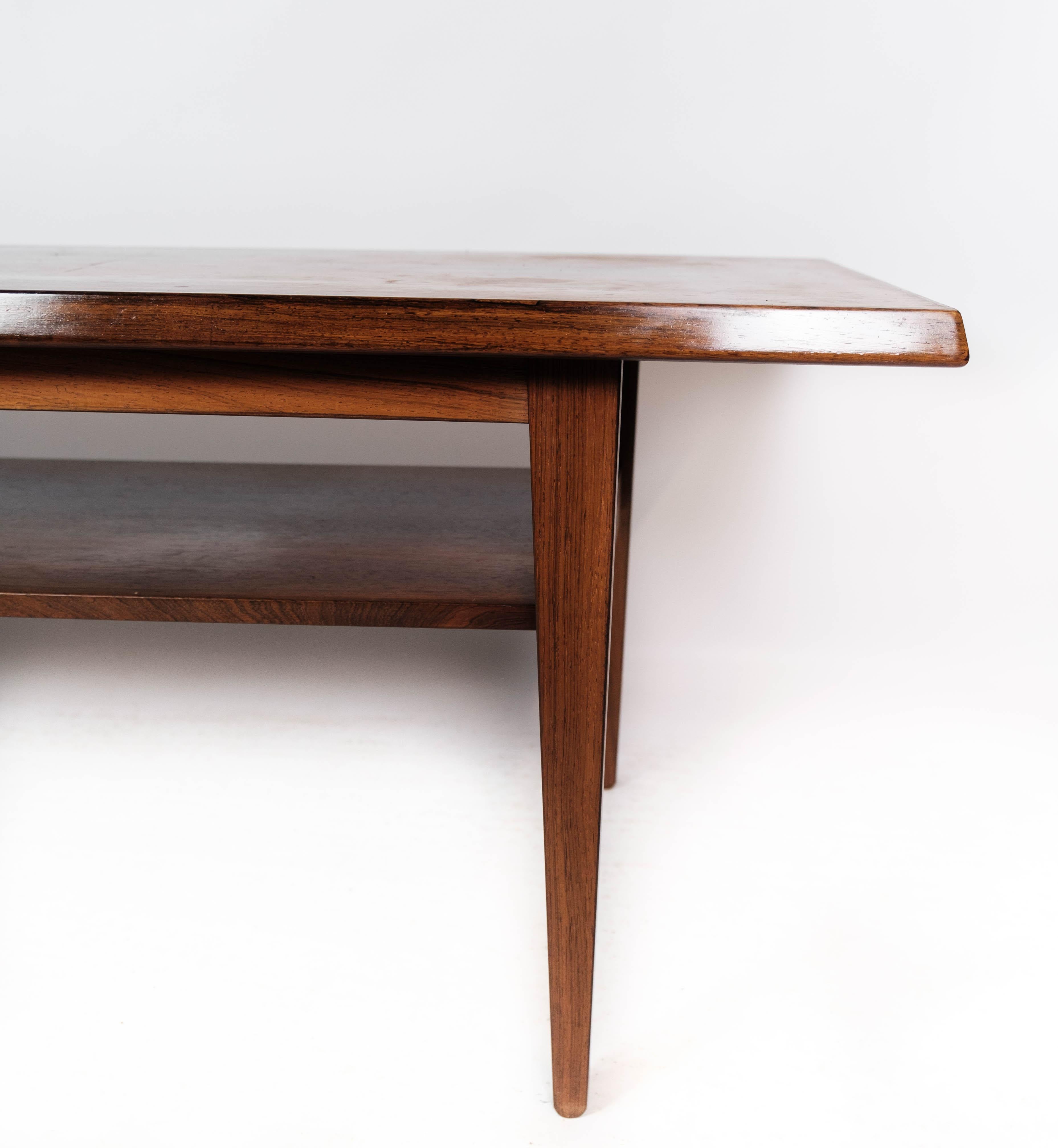 The coffee table crafted from rosewood with a shelf underneath the tabletop is a quintessential example of Danish design from the 1960s. Combining form and function with elegant simplicity, this piece embodies the principles of mid-century modern