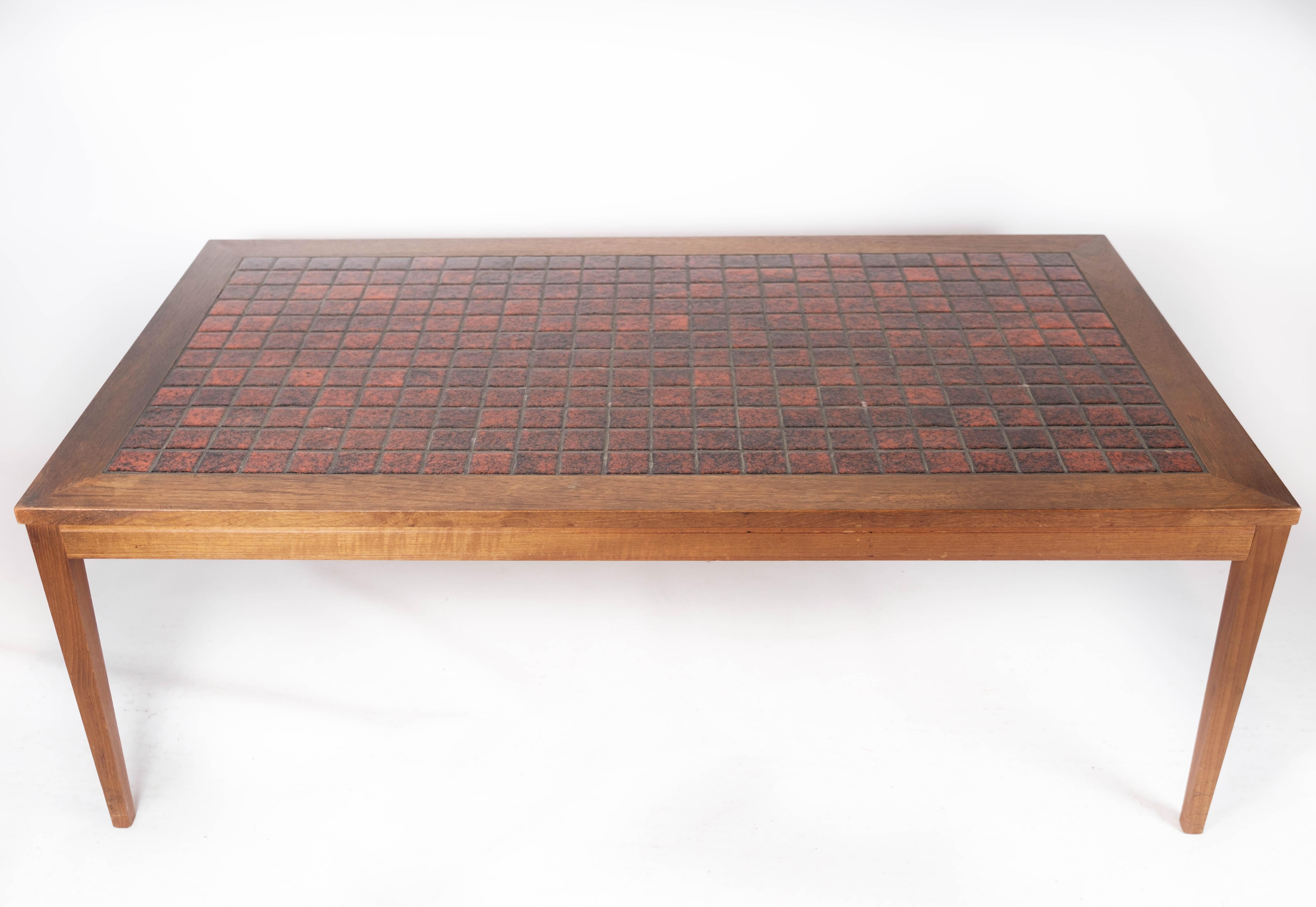 Crafted from teak wood and adorned with vibrant red tiles, this coffee table epitomizes the iconic Danish design of the 1960s. Its sleek lines and minimalist silhouette reflect the era's emphasis on functional yet stylish furniture.

Despite its