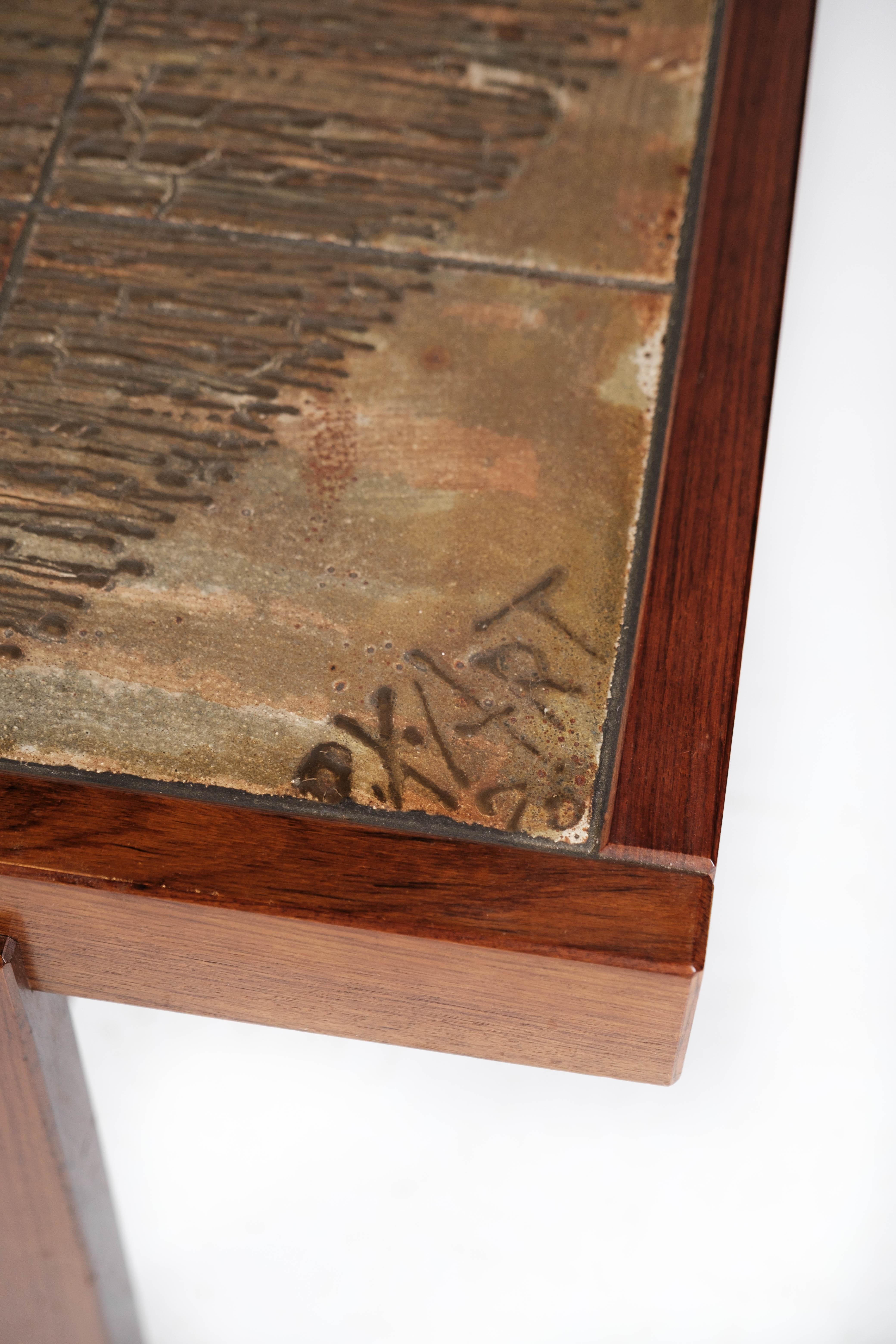 Dieser aus Teakholz gefertigte Couchtisch mit charmanten Fliesenakzenten verkörpert die ikonische dänische Designästhetik der 1960er Jahre. Seine klaren Linien und seine minimalistische Silhouette sind typisch skandinavisch und bieten sowohl