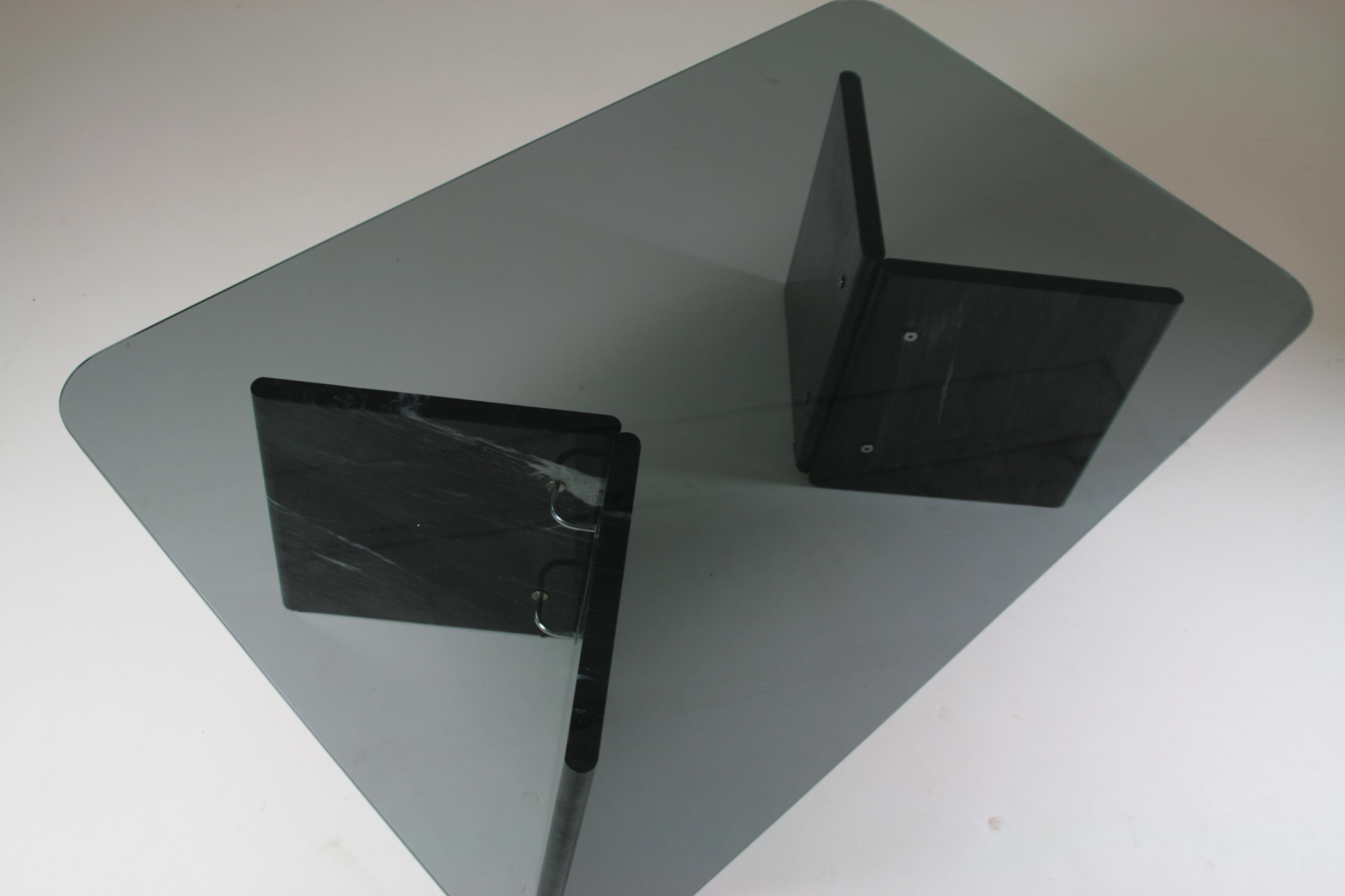 Italian coffee table with black marble legs and smoked glass top. Small chrome structures hold each pointed leg. A few barely visible micro-scratches. The whole thing is in very good condition. Dimensions: l 120 x d 75 x h40 cm.