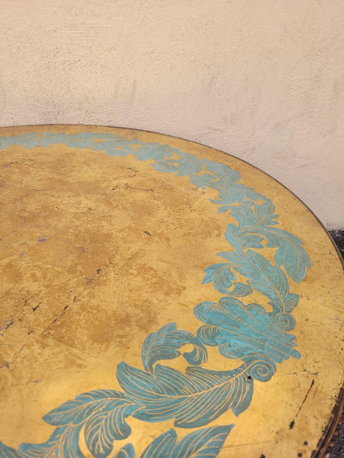 Round coffee table with wooden base carved with a floral decoration, and painted, surmounted by an eglomized glass top painted in blue/green and gold

Wear to the glass and to the base

Art deco period, 20th century

H48cm
Diameter