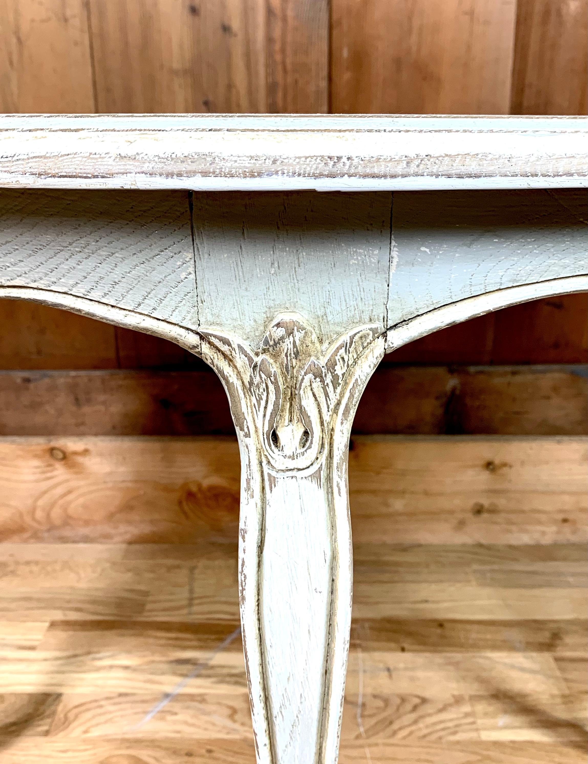 Charmanter runder Couchtisch im Stil Louis XV aus Holz. Dieser Tisch ist in blaugrauen Tönen patiniert, was ihm einen Vintage- oder Shabby-Chic-Look verleiht. Die Beine sind geschwungen und die Oberseite der Beine ist mit floralen Motiven