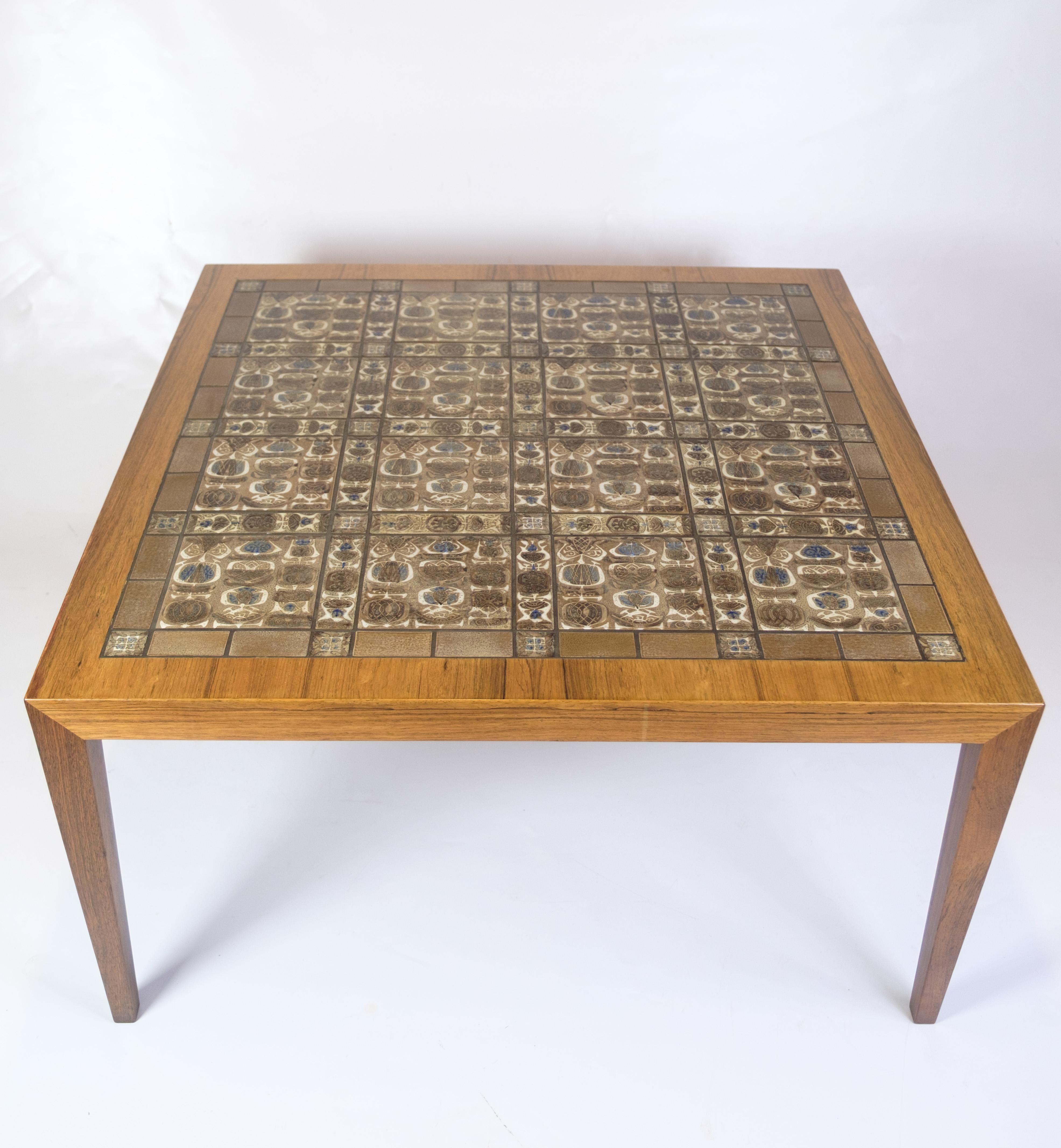 Coffee table designed by Severin Hansen in rosewood, produced by Haslev Møbelsnedkeri in collaboration with Royal Copenhagen. The tabletop is inlaid with ceramic “Baca” tiles by Nils Thorsson – each with its own unique expression in blue and earthy