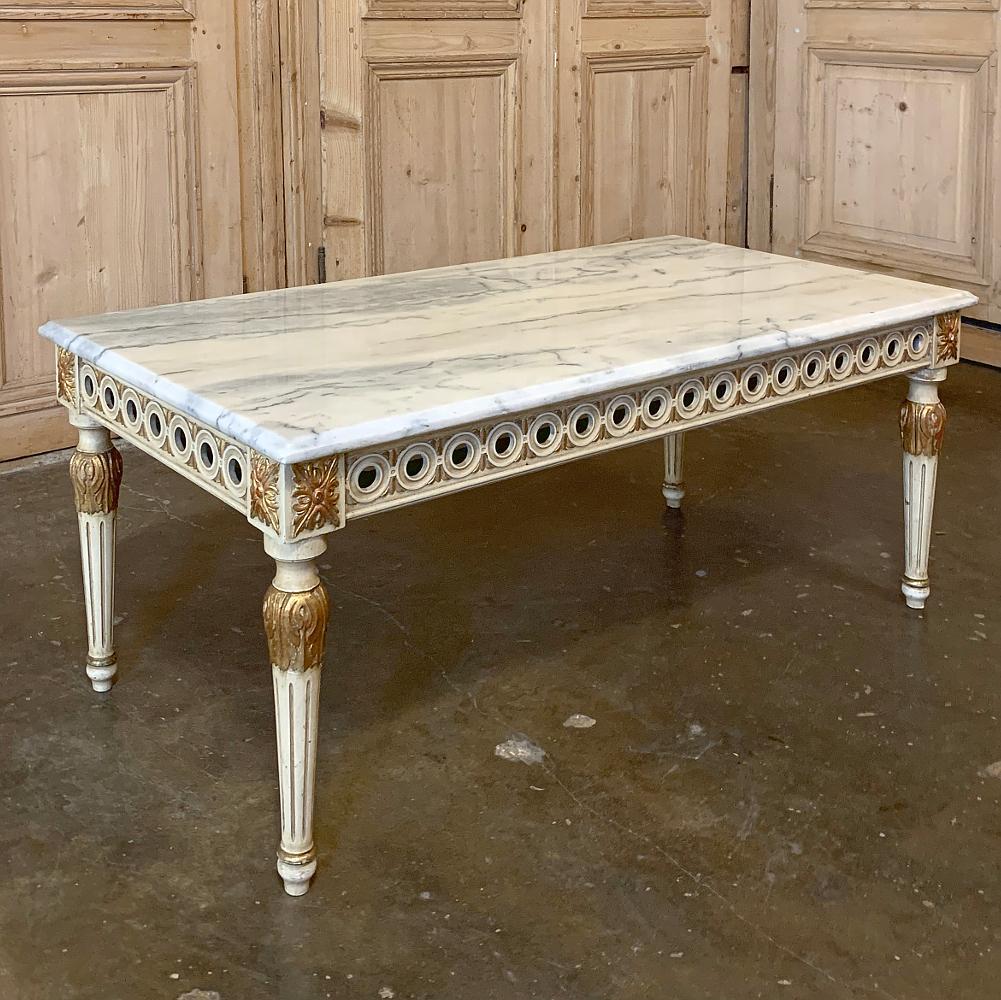 Midcentury neoclassical marble-top coffee table was hand carved from walnut by talented Italian sculptors, then given a patinated painted finish with the carved embellishments highlighted in gold for an opulent effect. Topped with beveled marble to