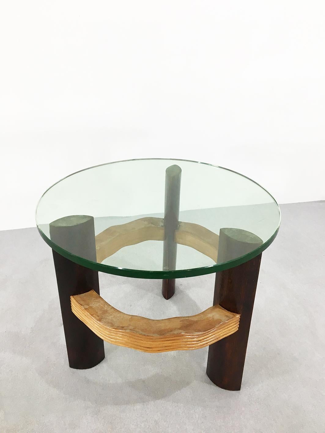 The table is made by the famous designer Osvaldo Borsani. Its top is made of 1 cm thick crystal glass. The feet that support its structure are made of ebony wood. We note that at the centre of each foot there is a circular circle made of cherrywood.