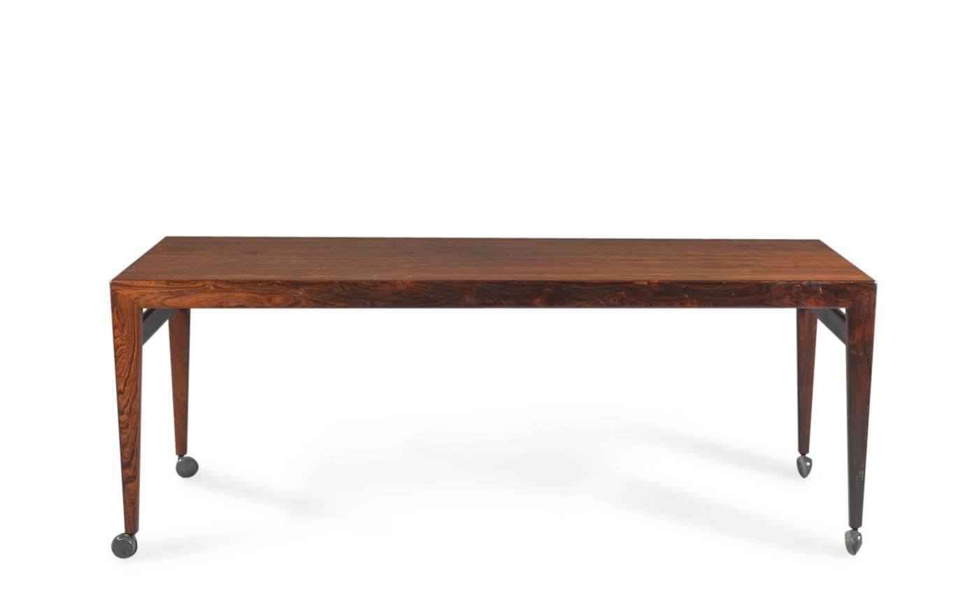 Johannes Andersen. Rectangular rosewood coffee table, two sliding extensions in black formica at the ends. Manufactured at Uldum furniture factory in 1960. Measures: H. 56 cm, L. 150 cm, B. 60 cm. On wheels.
Some traces of marks and wear.