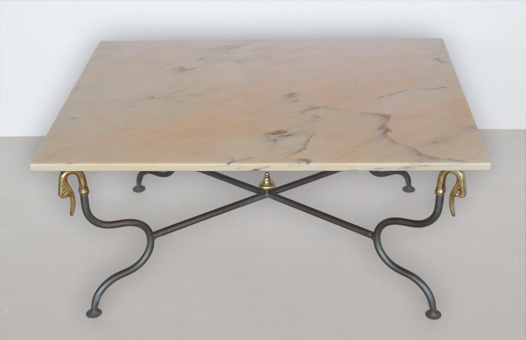 Coffee table  with Pink Portogallo marble  top and  wrought metal base . This coffee table will make a  stately addition to a modern decor. Its sleek silhouette is completed with a rusty finished metal ending in the corners with brass swan