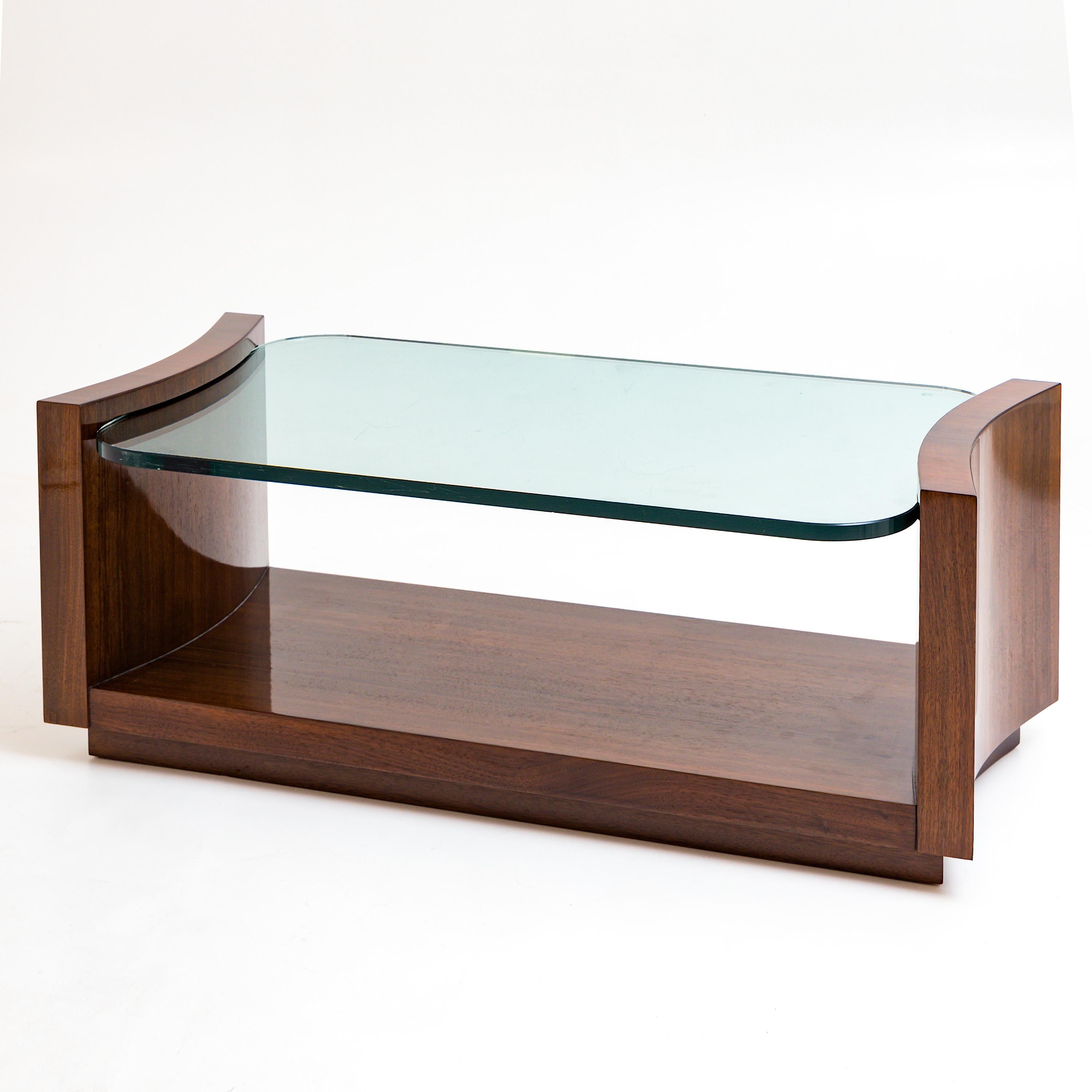 Rectangular coffee table with concave indented sides and thick rounded glass top. The furniture has been expertly refurbished and hand polished.