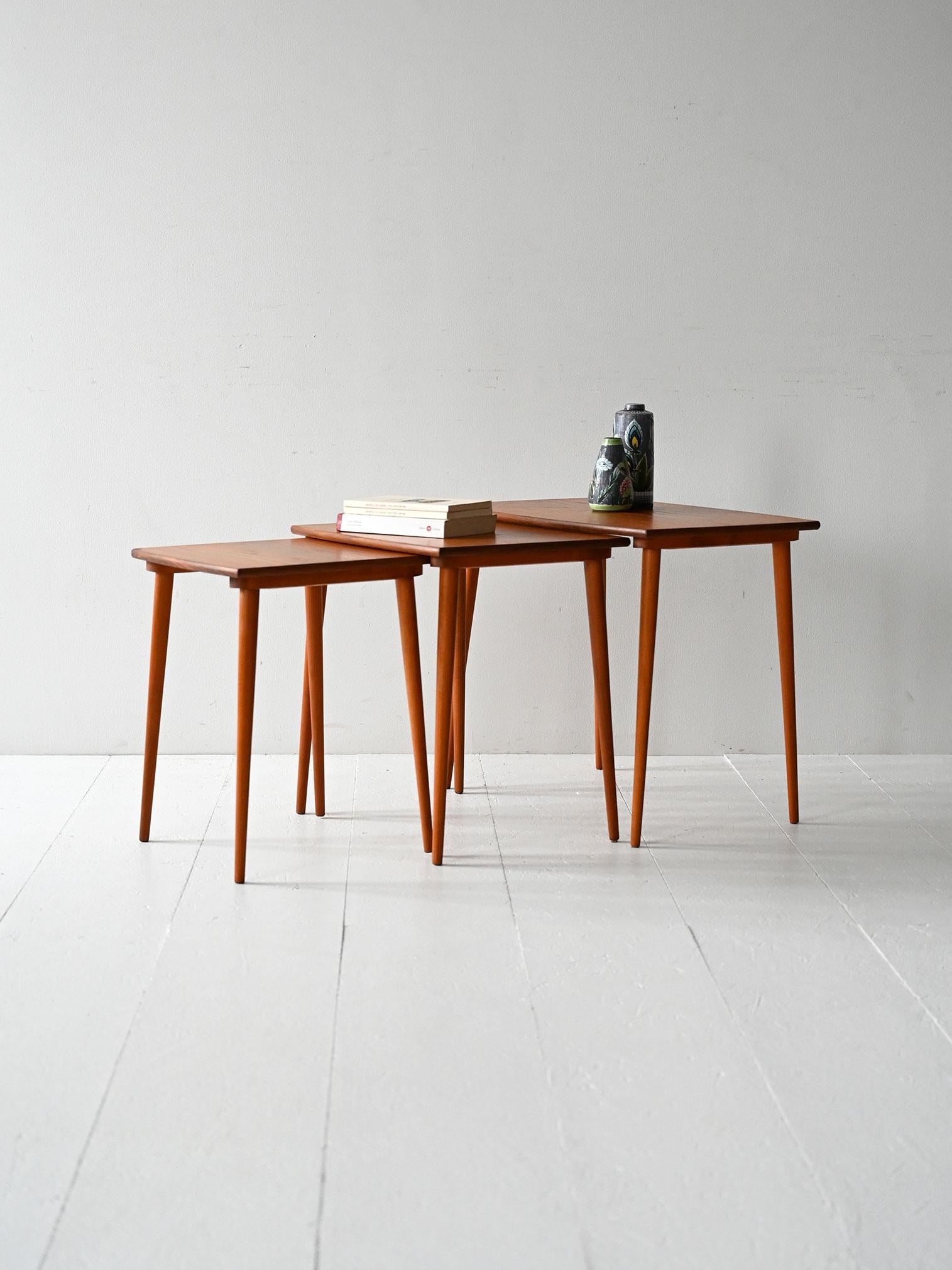 Scandinavian 1950s/60s coffee tables with sliding interlocking system, teak frame, and thin tapered legs.

Trio of Scandinavian 1950s/60s teak coffee tables with a slide-in interlocking system that allows them to be stacked compactly. The