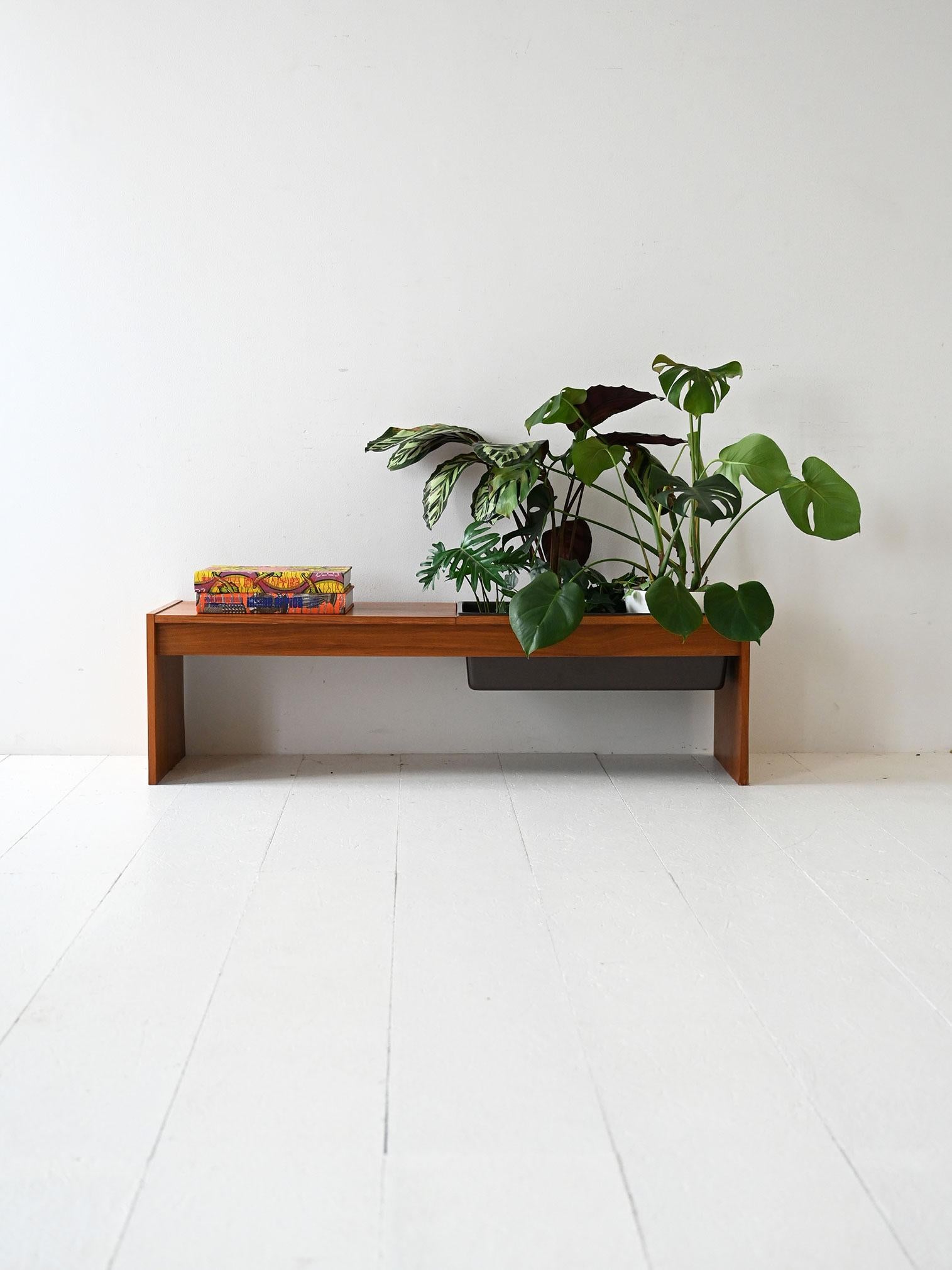 Une table basse en teck des années 1960 aux lignes essentielles, avec un porte-fleurs en plastique noir intégré dans le cadre.

Table basse scandinave des années 1960 en teck au design minimaliste et élégant. La structure linéaire abrite un