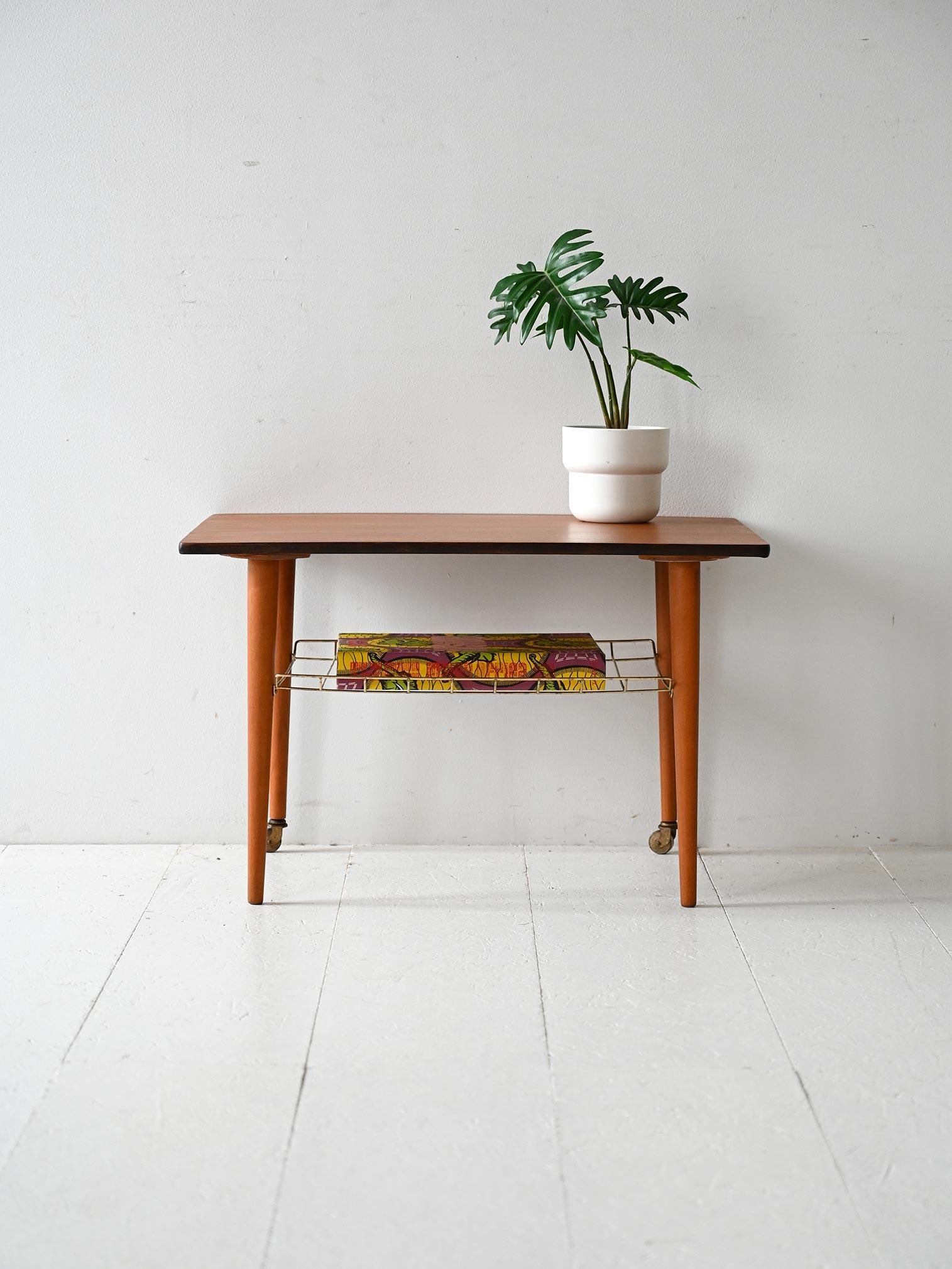 Coffee table scandinavo anni 60 con piano in teak con mensola in ottone e ruote.

Coffee table scandinavo vintage degli anni 60 con piano in teak e gambe affusolate in faggio tornito. La struttura è arricchita da una mensola in ottone dal disegno