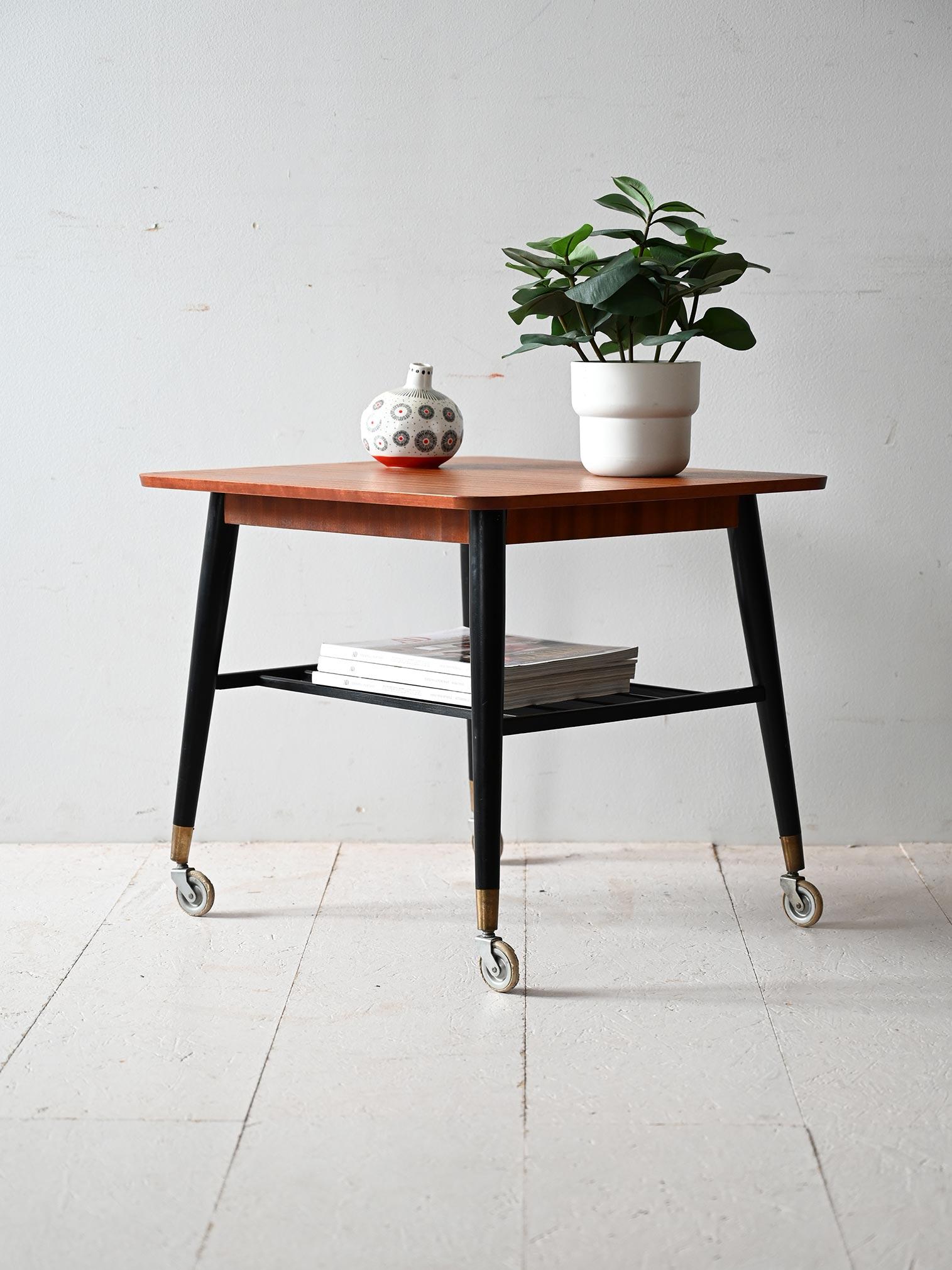 Mesa de centro escandinava de los años 50/60 con tablero de teca, patas negras con detalles de latón, estante de listones para revistas.

Mesa de centro escandinava de los años 50/60 con tablero de teca de veta regular y esquinas redondeadas.