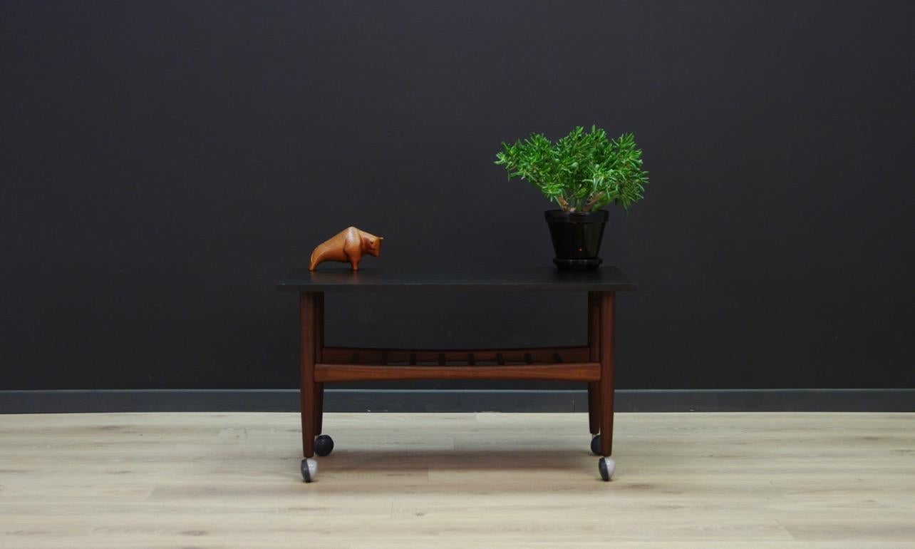 Original table from the 1960s-1970s, Danish design, top coated with black paint. Construction made of teak. The legs have mounted wheels, so the table can be moved freely. An additional advantage is the shelf mounted below the countertop. Preserved