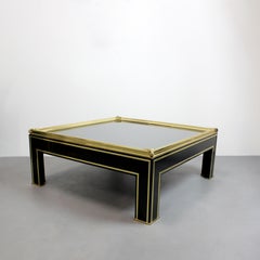 Coffee table with a black lacquered wood frame, gilt brass details, and a mirror