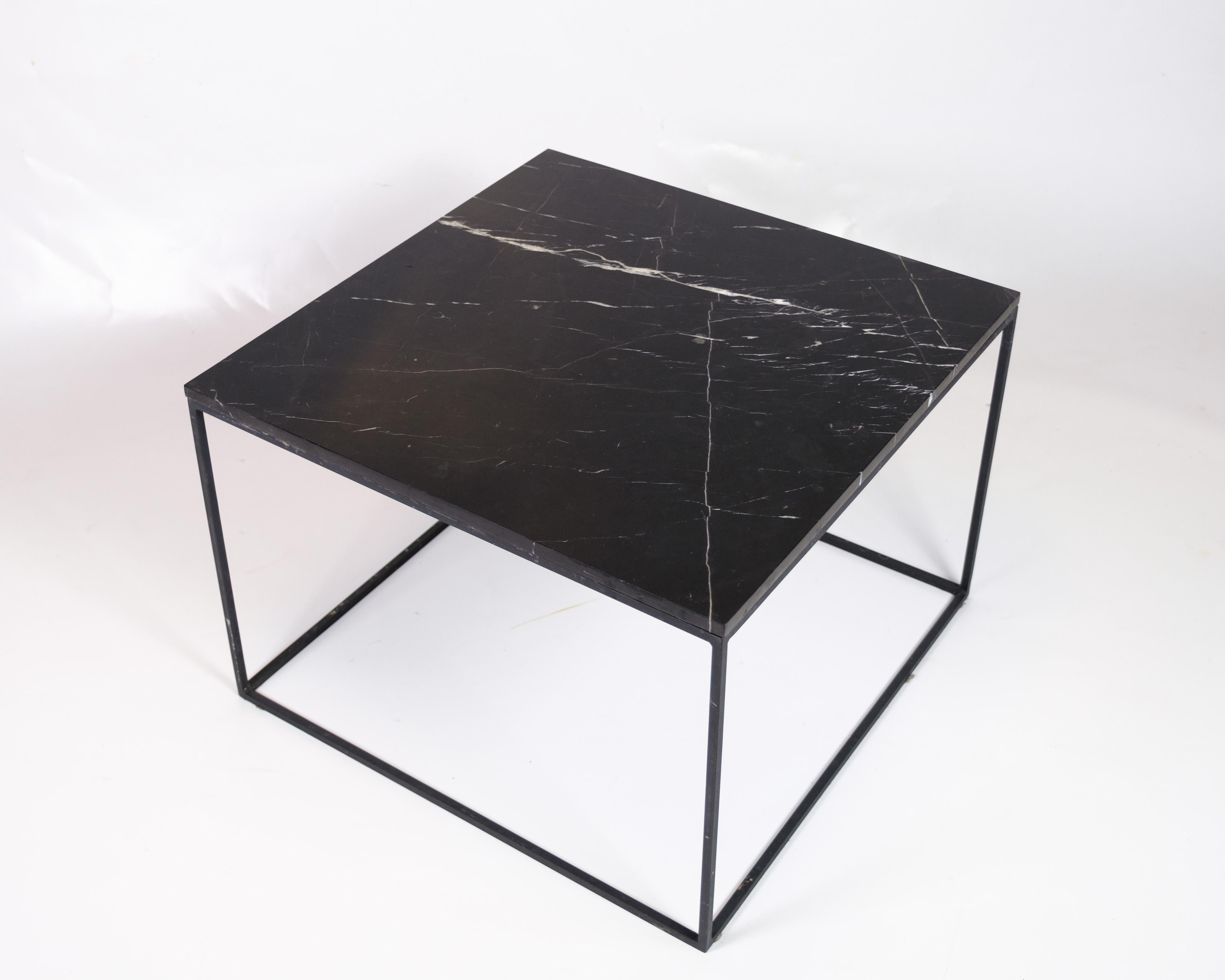 Table basse avec plateau en marbre noir et structure en métal. La table allie l'aspect solide et élégant du marbre au design moderne et minimaliste de la structure métallique. Le plateau en marbre noir présente de magnifiques motifs de grain