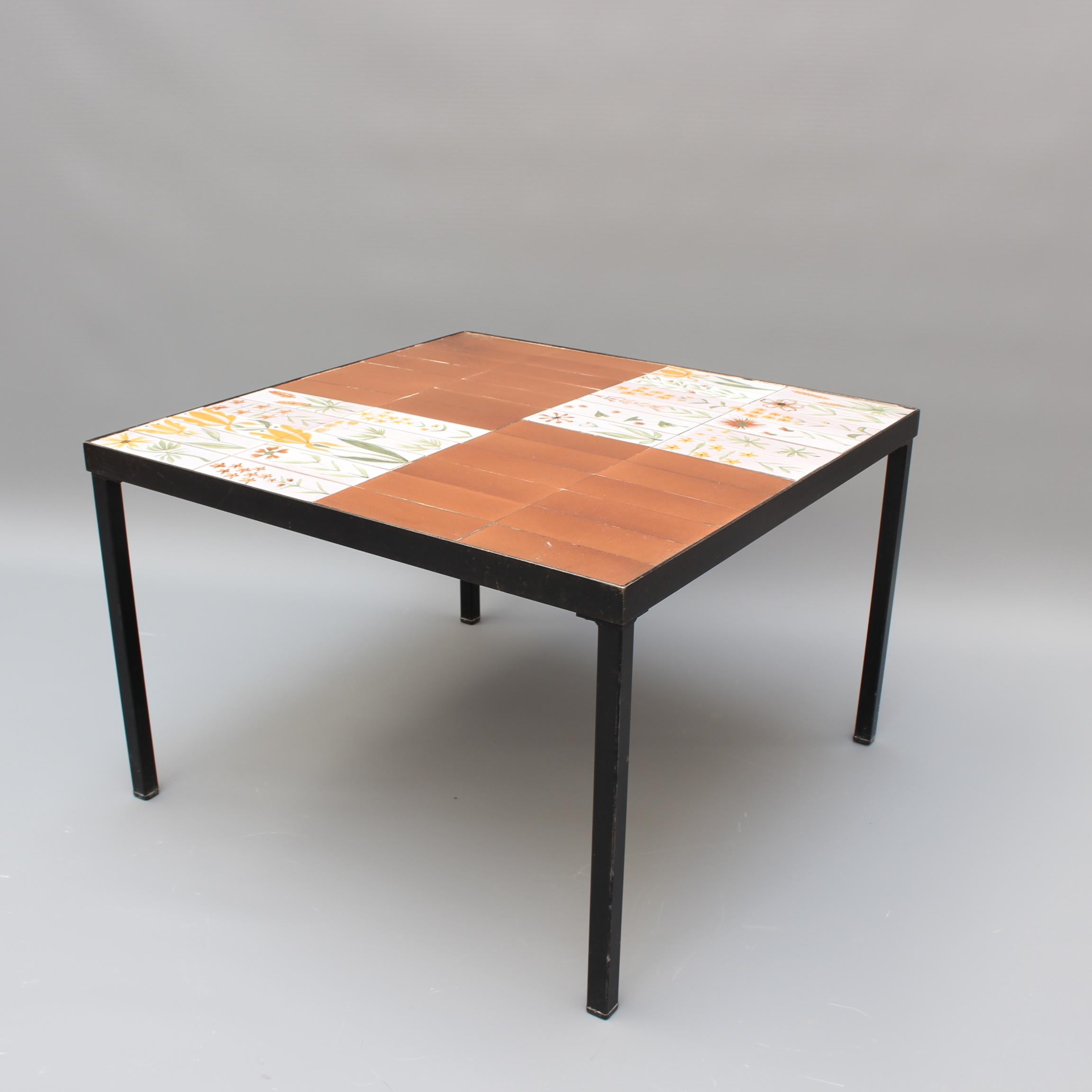 Table basse avec des carreaux de céramique décoratifs de l'artiste Roger Capron. Cette charmante table (datant des années 1970) est un exemple typique de la collection Capron. Il y a des tuiles sur le thème du jardin avec une variété de belles
