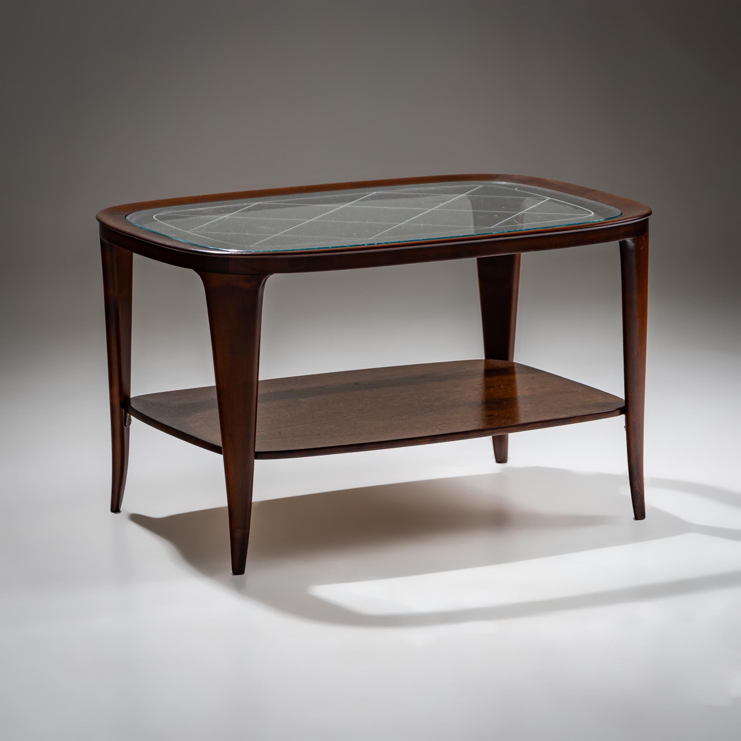 Table basse d'Italie avec un plateau en verre transparent soutenu par un cadre élégant aux coins arrondis et à quatre pieds. Le design combine des lignes épurées avec des matériaux de haute qualité et reflète le style du milieu du siècle. Le plateau