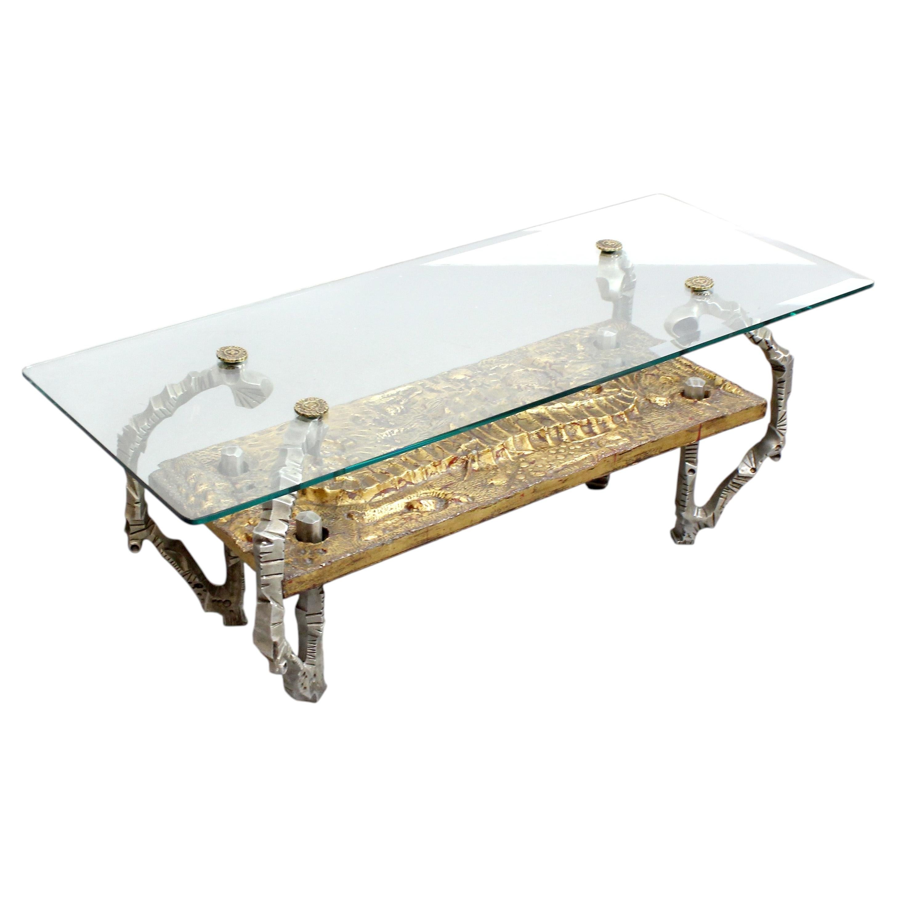 Coffee table with glass top, supported by a sculptural cast metal structure For Sale
