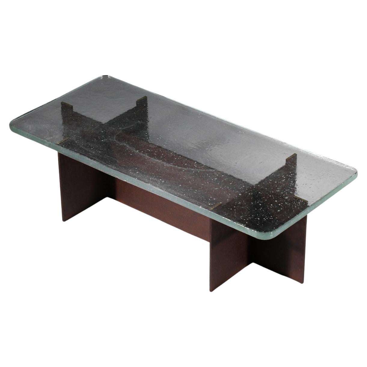 Table basse avec plateau en verre transparent vintage et base moderne en acier.